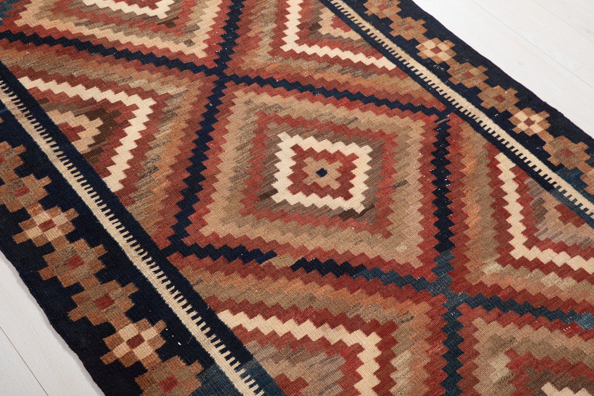 Diagonal close-up of the concentric diamond pattern showing flatweave texture.