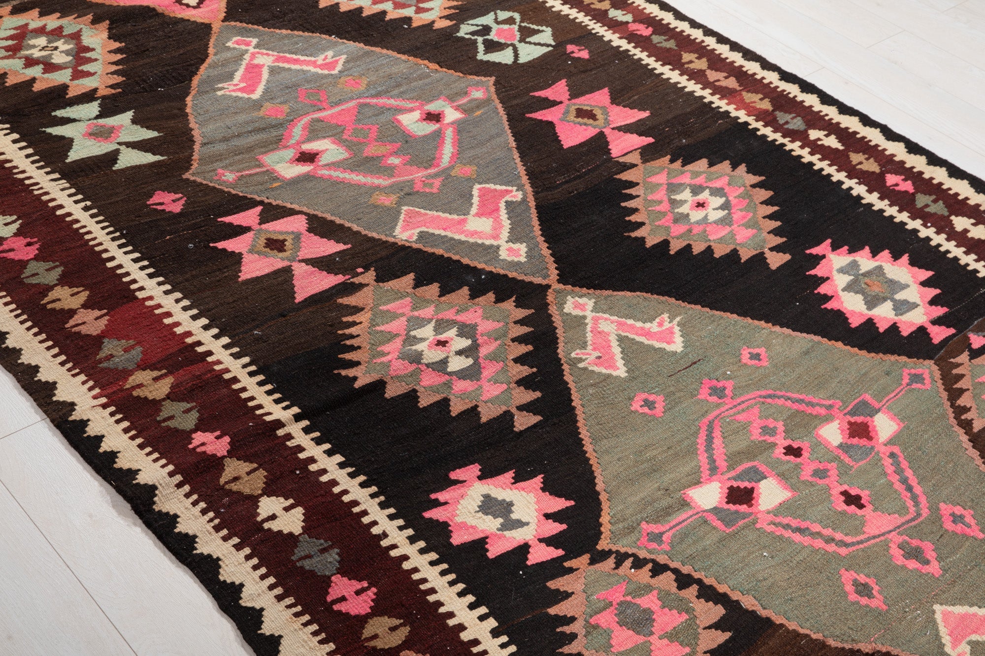 Diagonal close-up of the kilim's diamond medallions featuring stylized bird motifs.