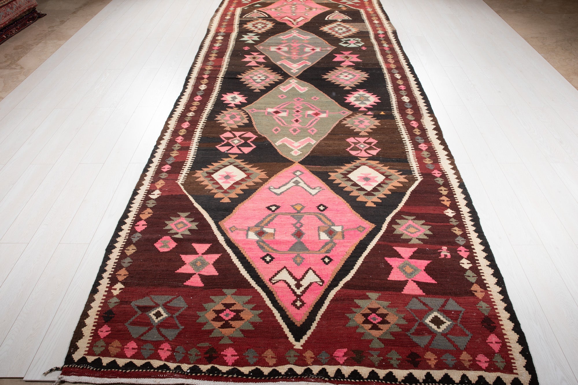 Full-length perspective of the Persian kilim runner from the opposite end, showing its fringe.