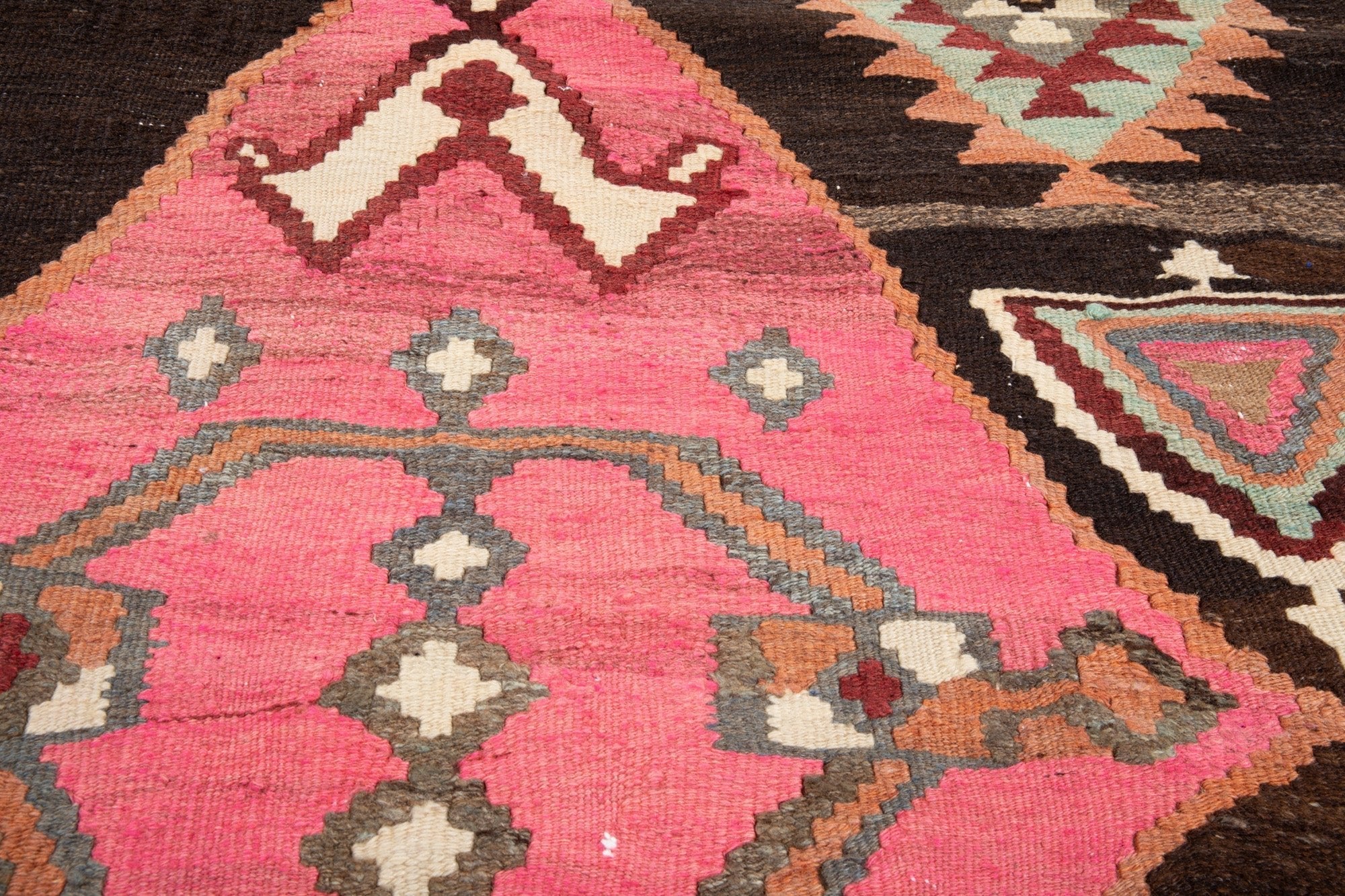Extreme close-up of the pink diamond medallion, revealing the handwoven wool kilim texture.