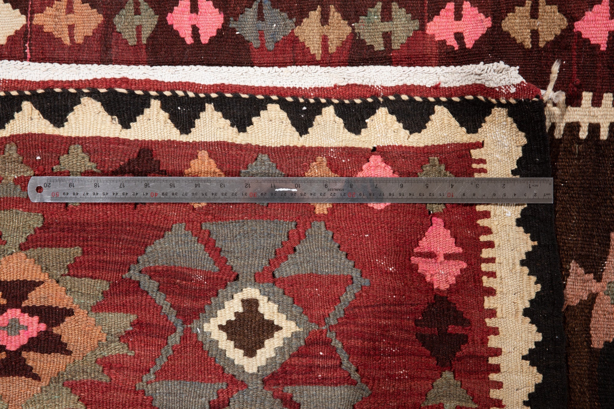 Ruler measuring the kilim rug's border width, confirming accurate size for buyers.