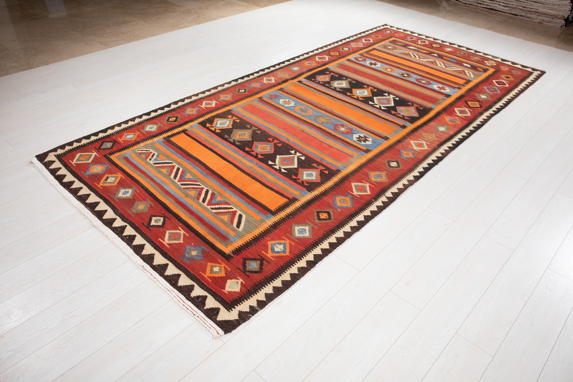 Angled view of the multicolor Shiraz kilim runner laid out on a wood floor.