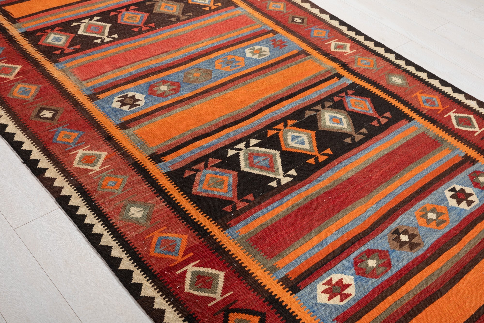 Diagonal close view of the kilim's striped bands and diamond medallions.