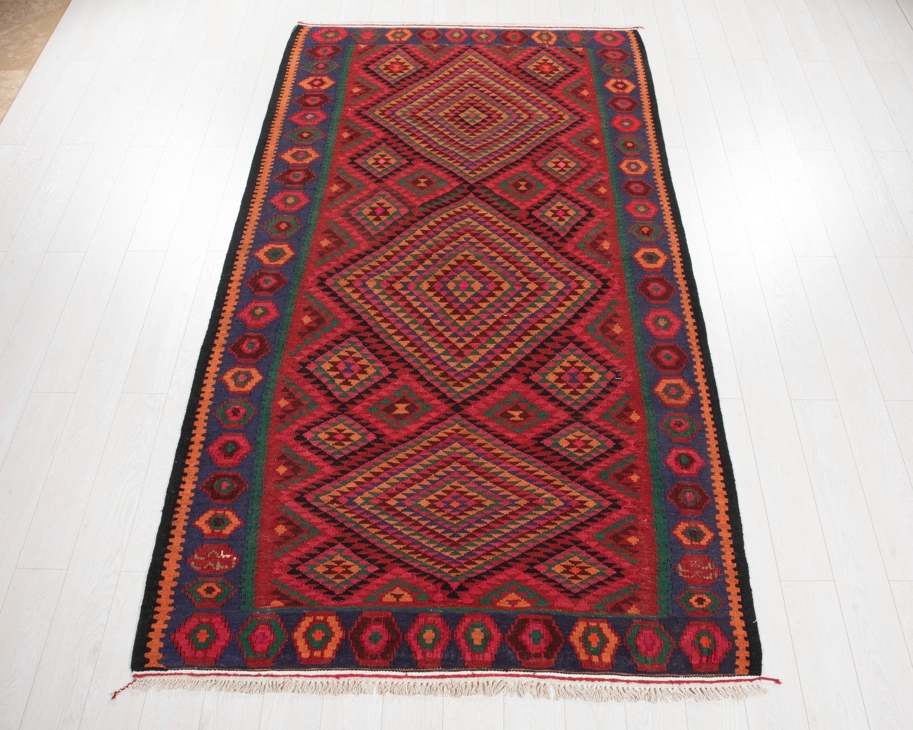 Full view of the vintage Persian Shiraz kilim rug in bold red geometric diamond design.