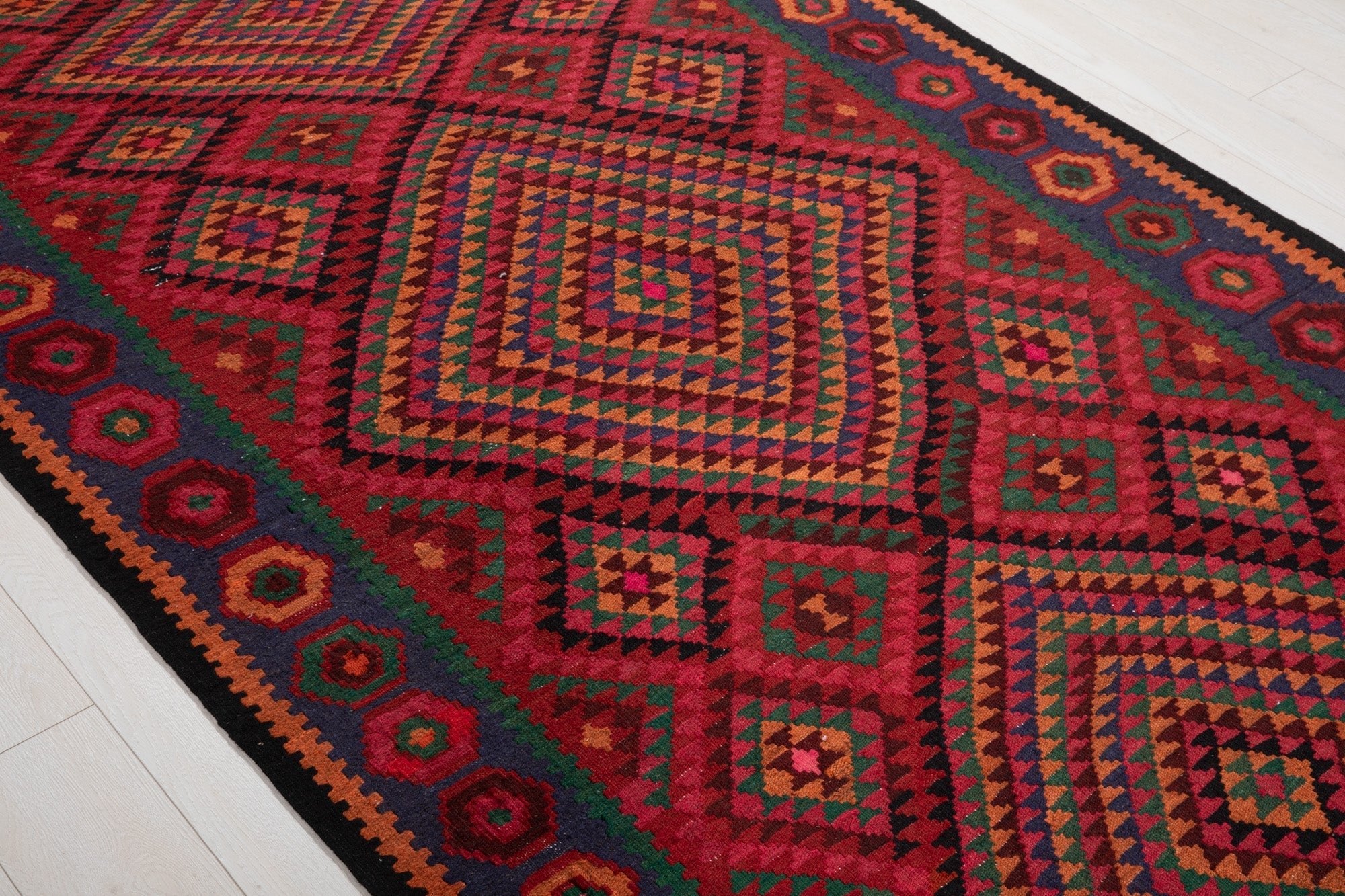 Diagonal close view of the Shiraz kilim's concentric diamond geometric pattern.