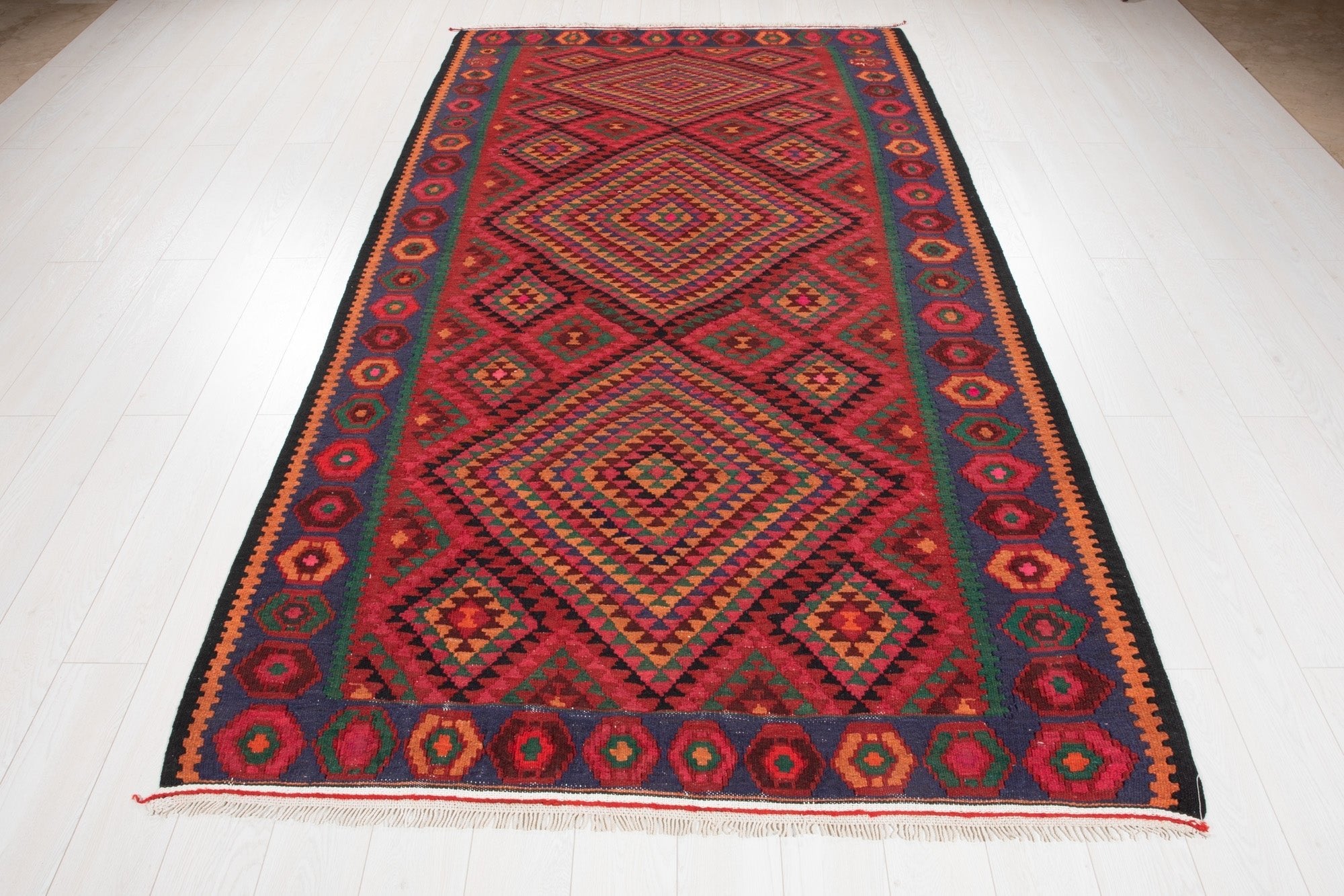 Full-length view of the Persian kilim rug from the opposite end, showing its fringe.
