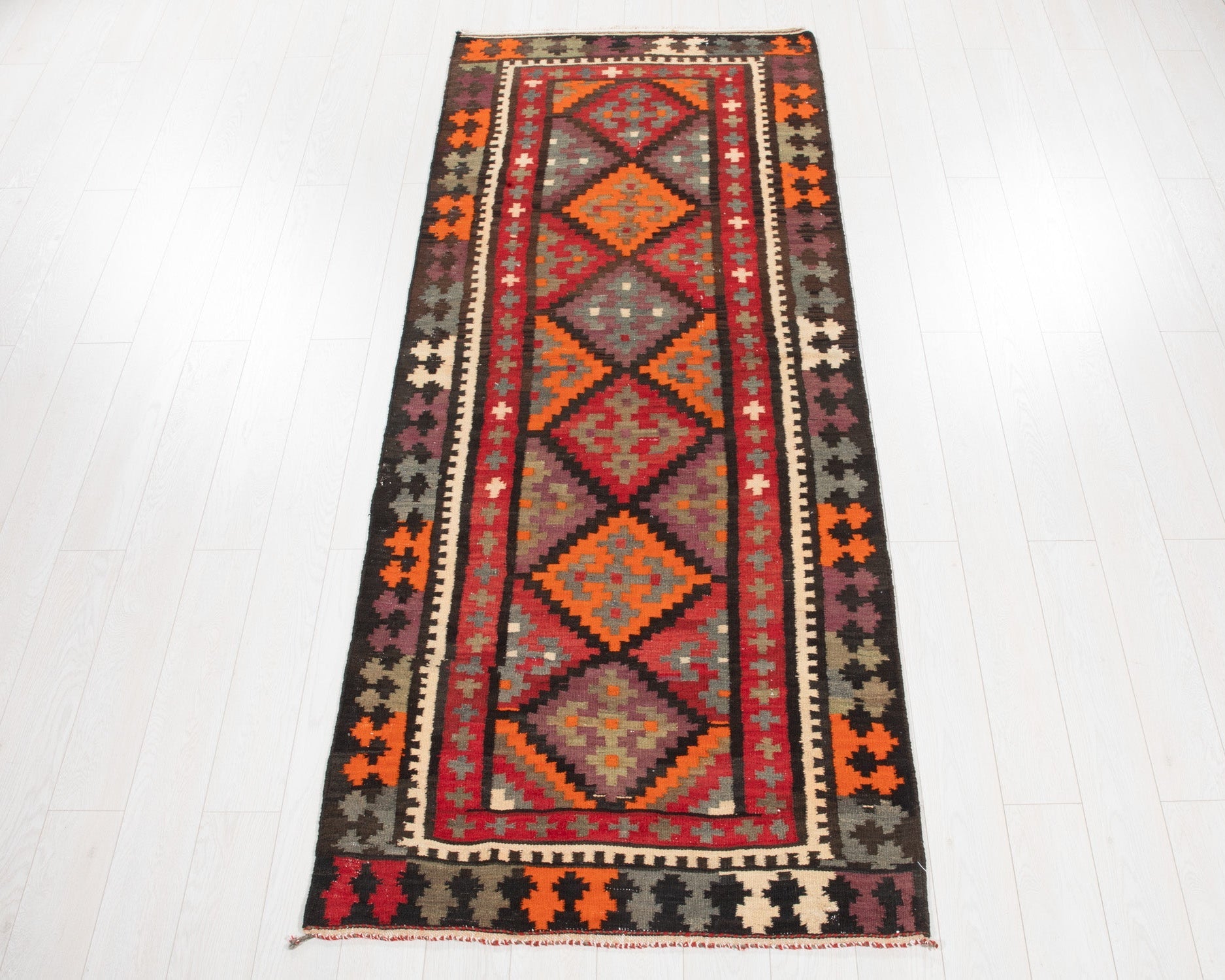 Full view of the vintage Persian kilim runner in orange, red and brown geometric diamonds.