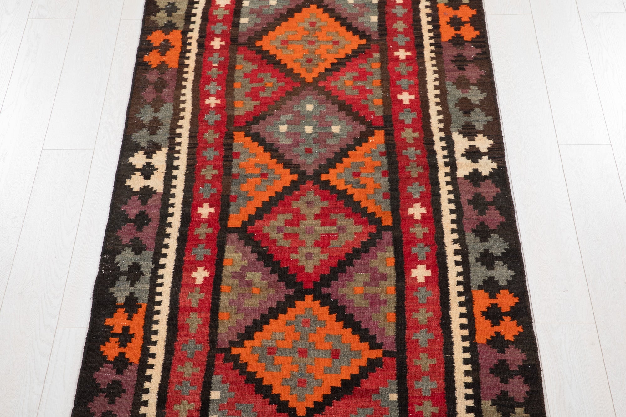 Top-down view of the kilim runner's stacked diamond medallions and cross motifs.