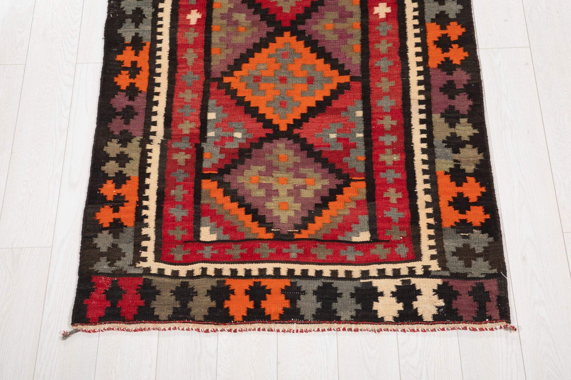 One end of the kilim runner showing the diamond medallion and fringed edge.