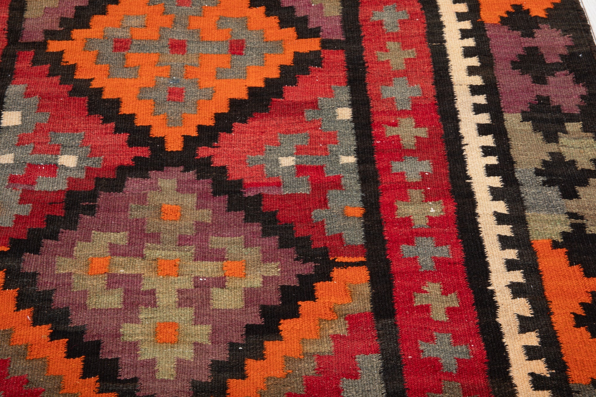 Close-up texture of the handwoven wool kilim's diamond and cross pattern.