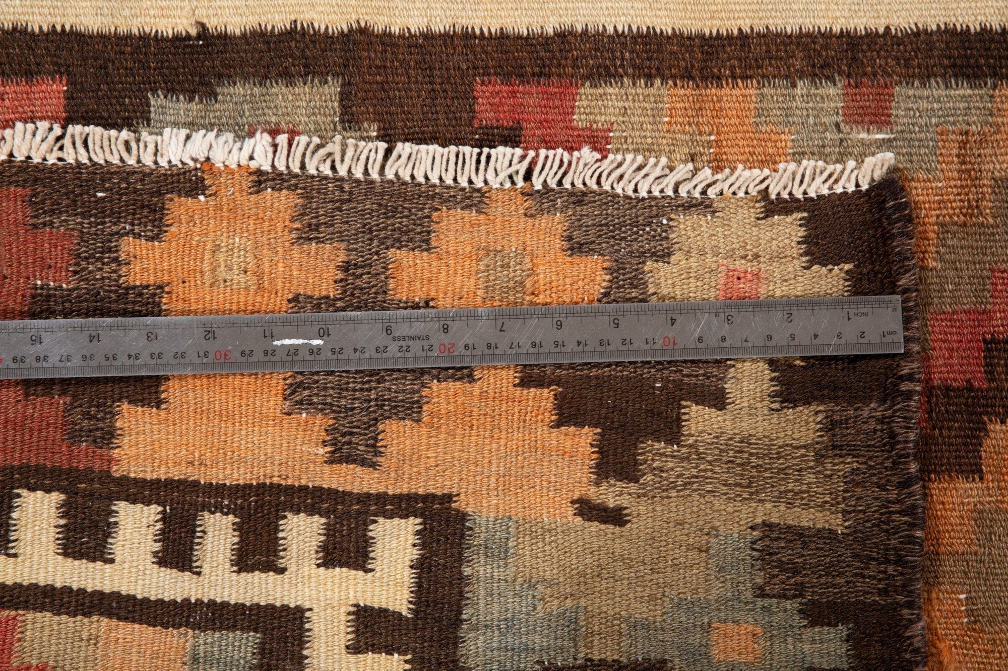 Ruler measuring the kilim's cross-motif border next to its fringe.