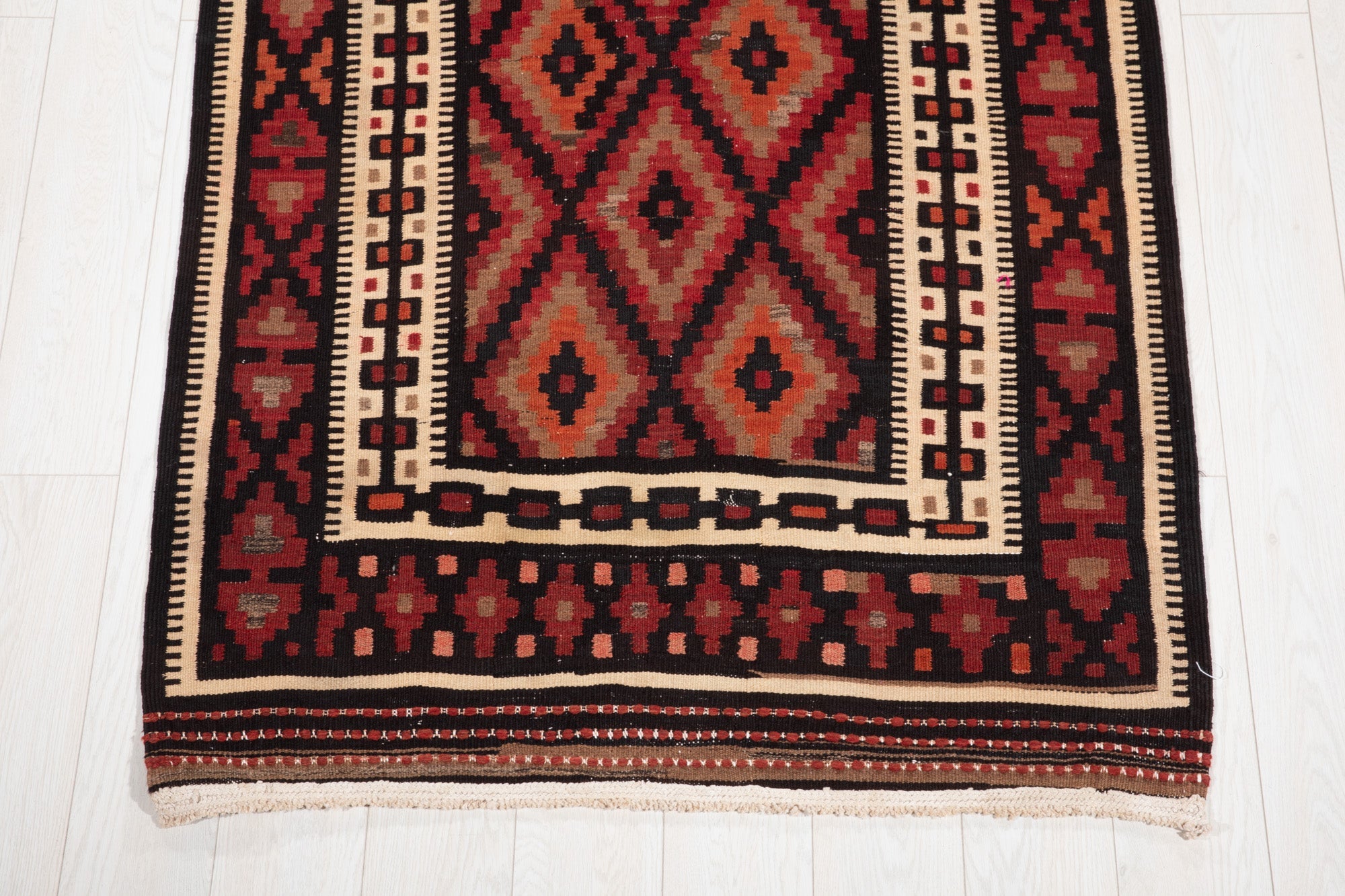 One end of the kilim runner showing its diamond medallion and geometric border.