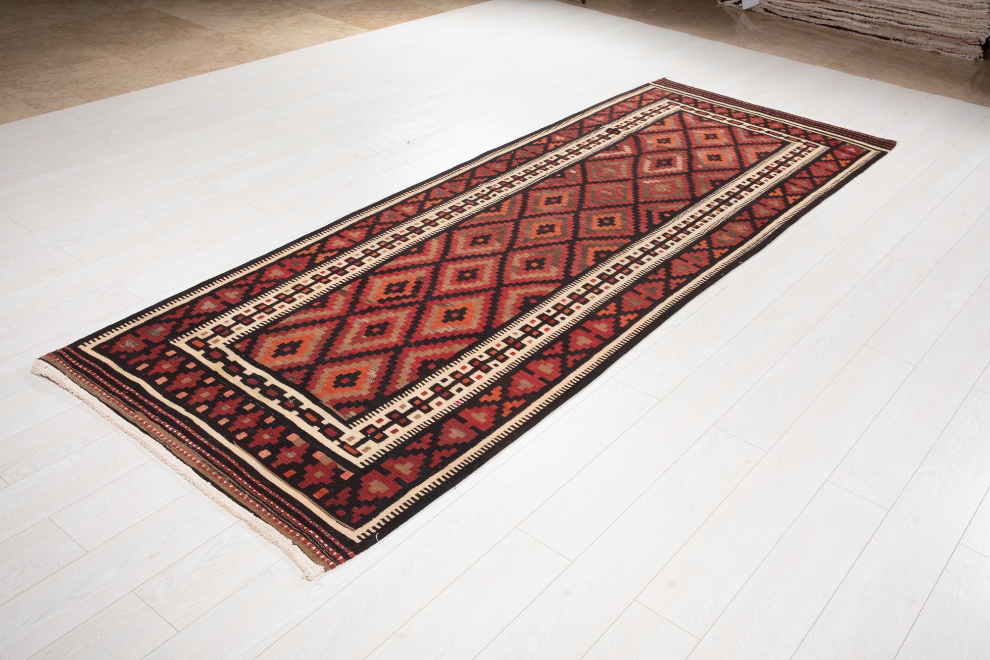 Angled view of the Persian kilim runner's diamond pattern on a wood floor.