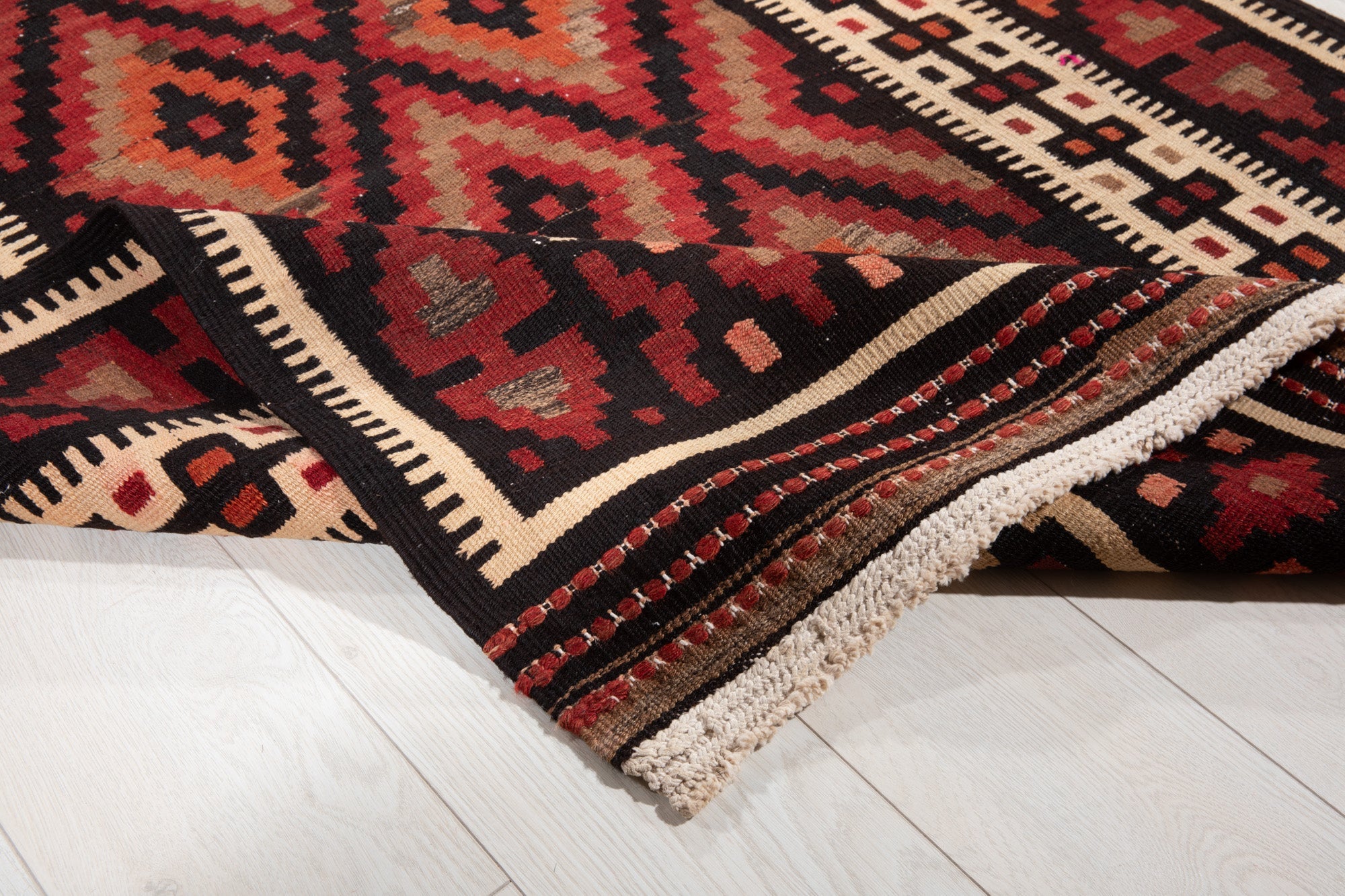 Close-up of the handwoven wool kilim's diamond weave and fringe texture.