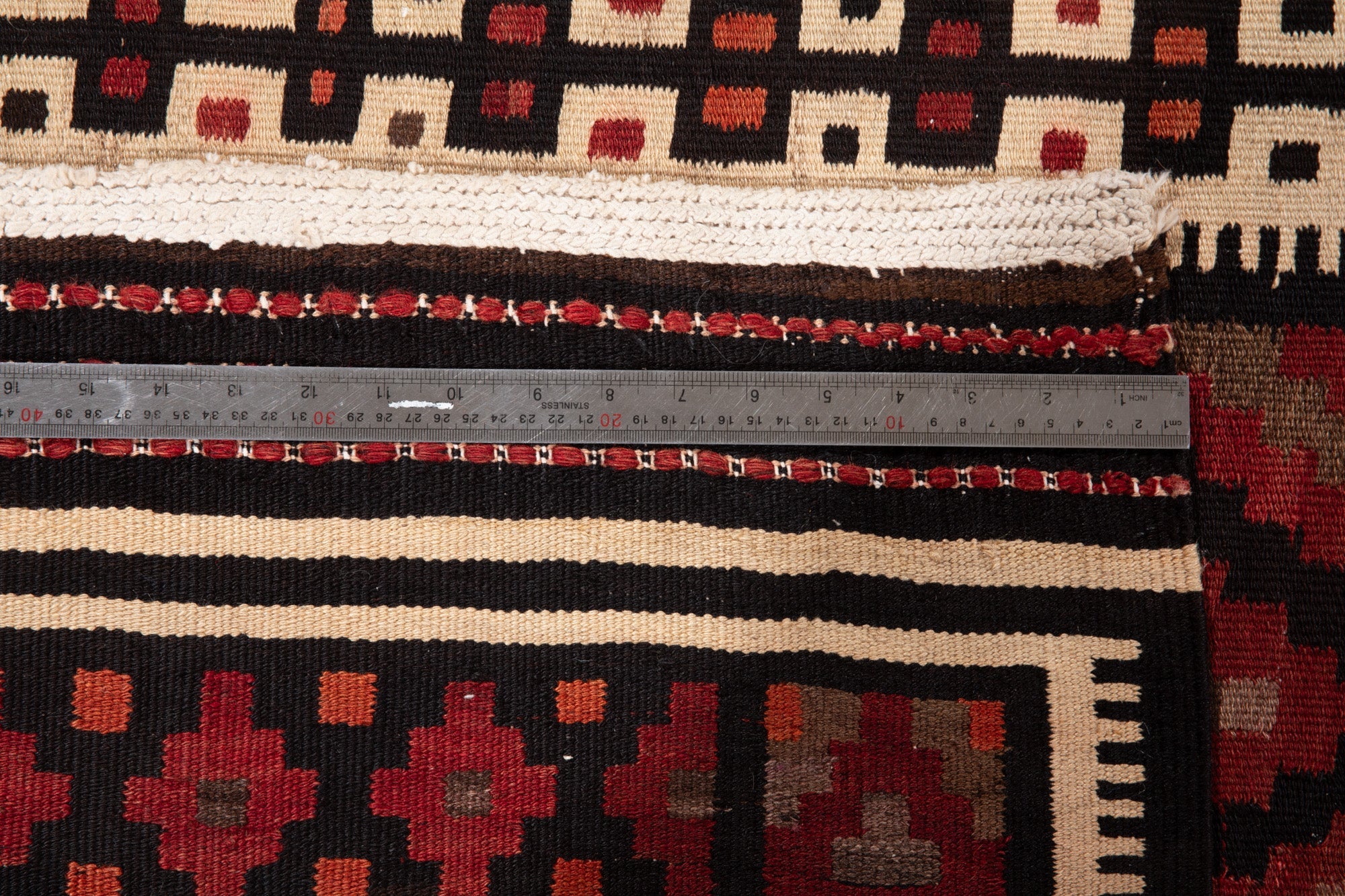Corner view of the kilim runner's fringed end and diamond border pattern.