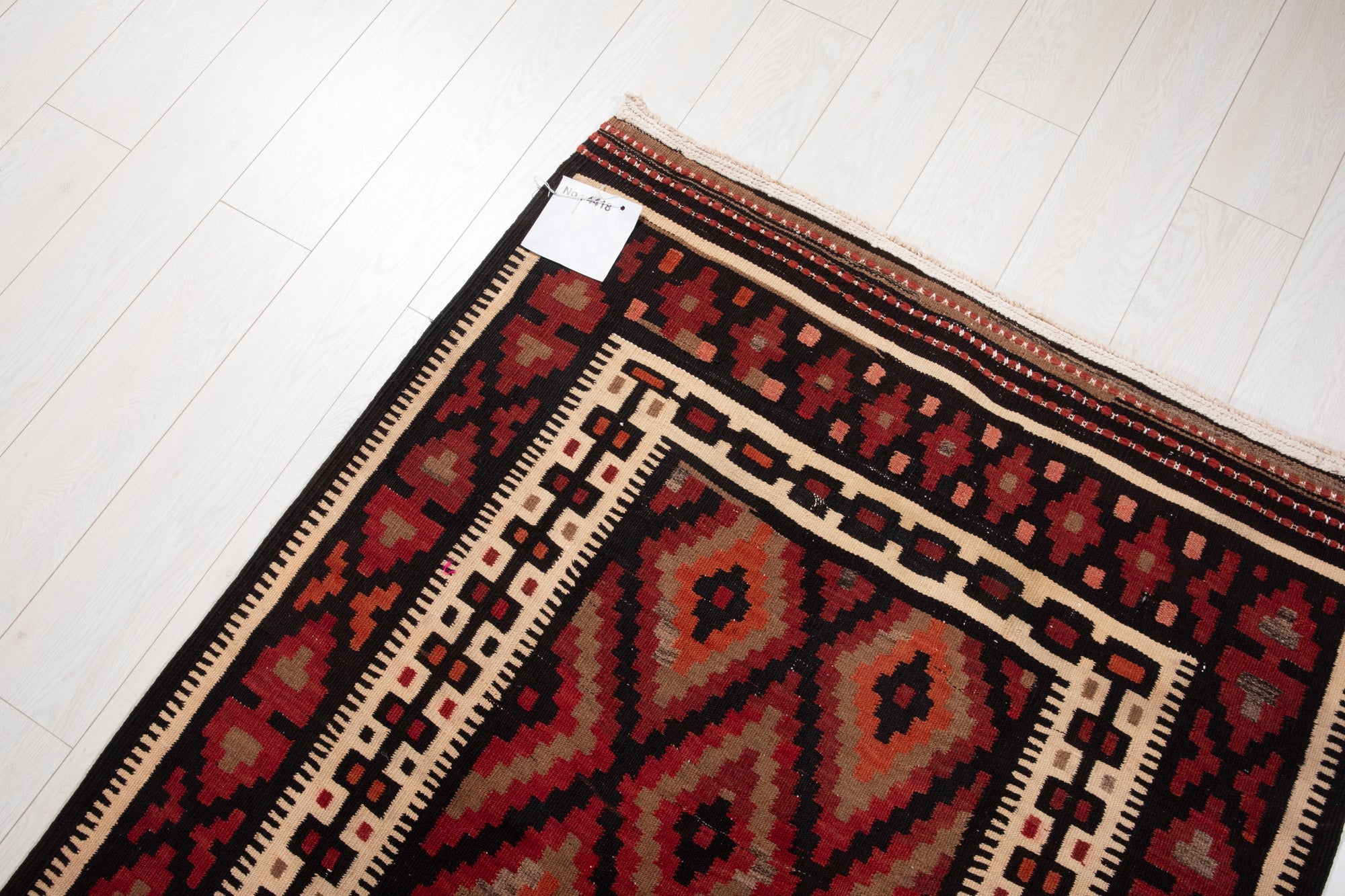 End corner of the vintage Persian kilim runner showing its fringe and diamond border.