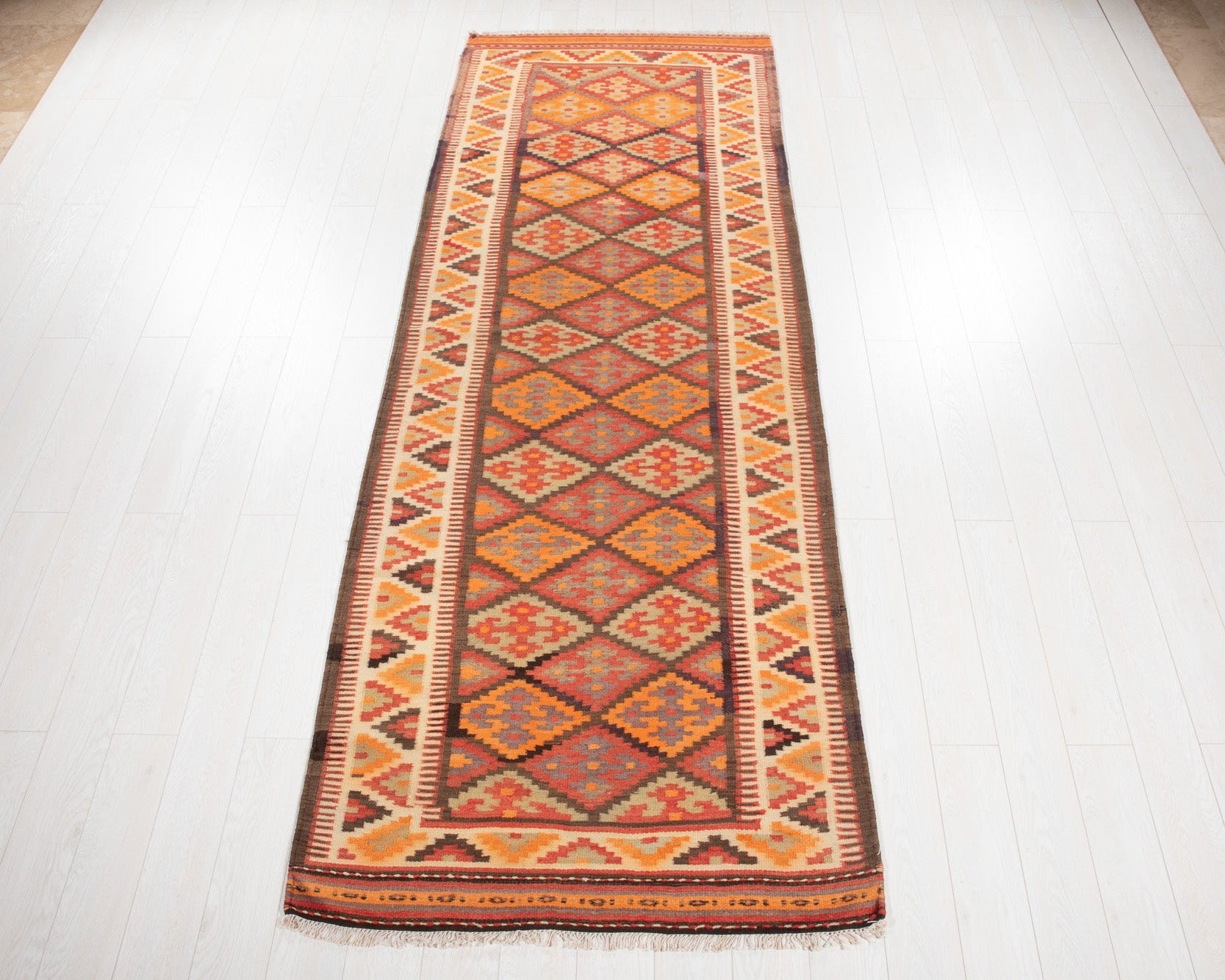 Full view of the vintage Persian Shiraz kilim runner in rustic red and orange diamonds.