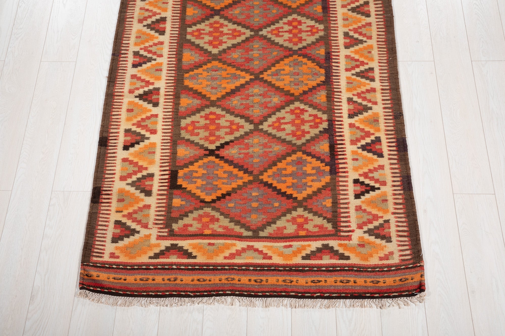 One end of the kilim runner showing its diamond pattern and fringed edge.