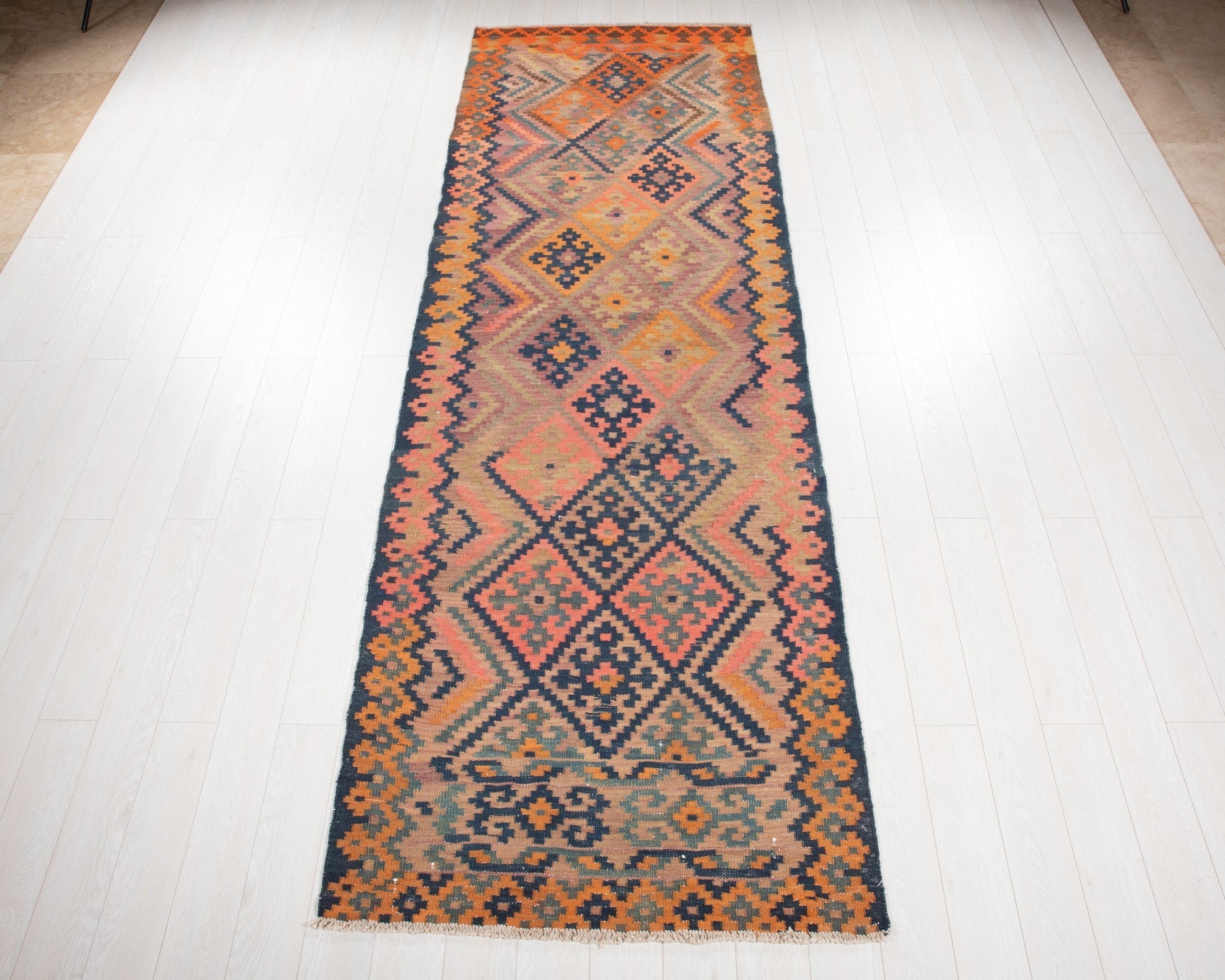 Full view of the antique Persian runner rug in orange, burgundy and navy geometric diamonds.