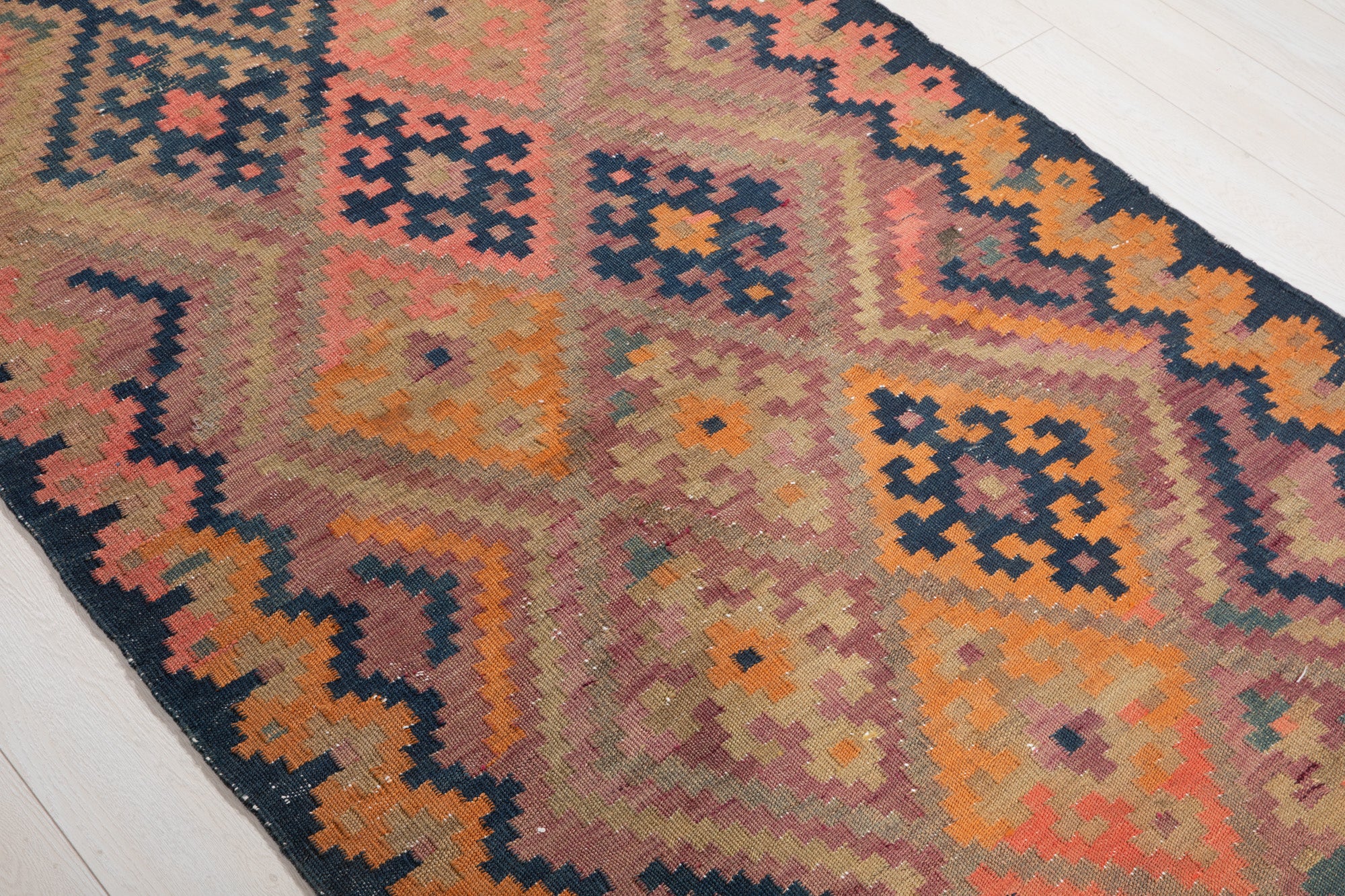 Diagonal close view of the antique runner's diamond and cross motifs.