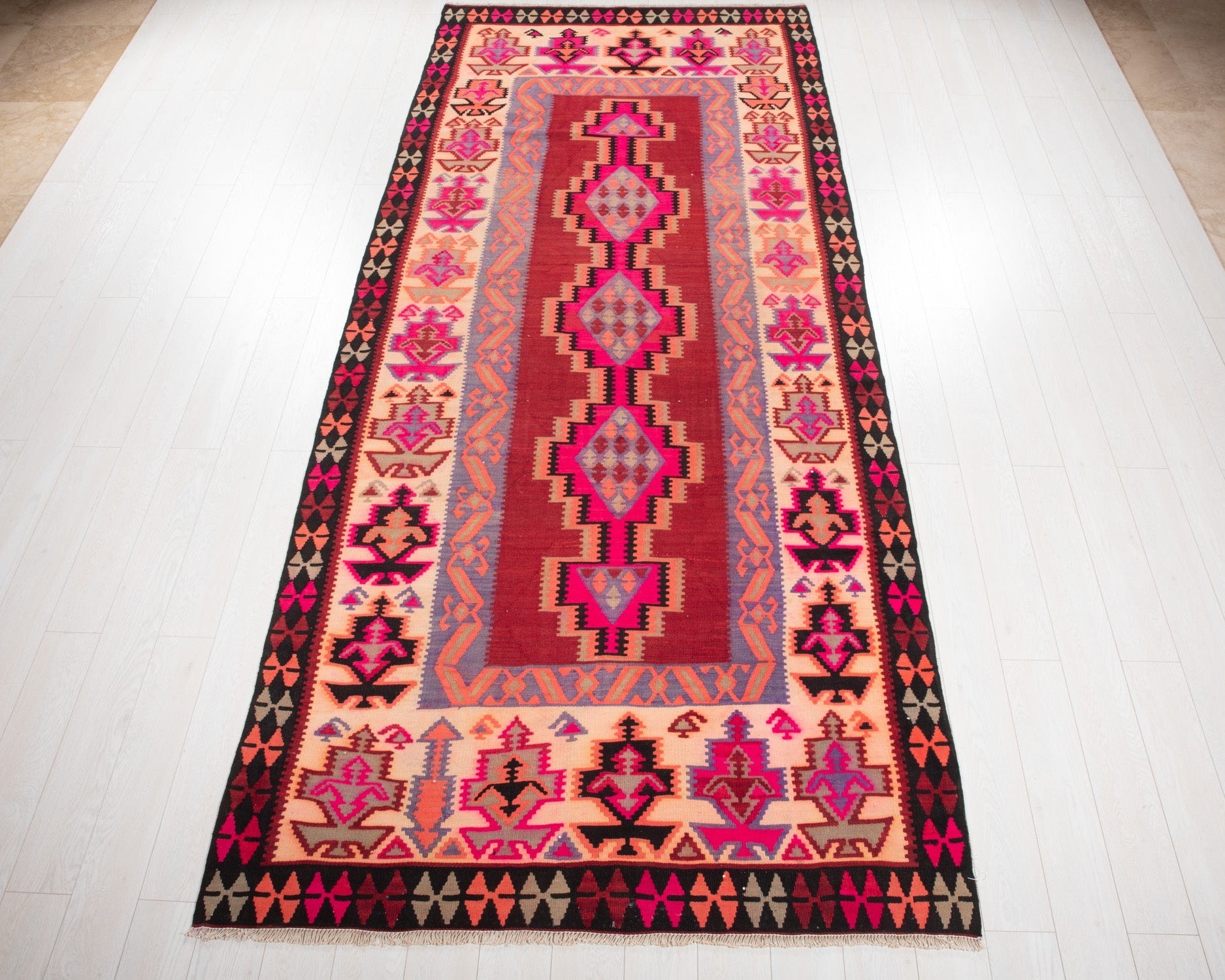 Full view of the vintage Persian Shiraz kilim rug in pink and beige geometric diamonds.