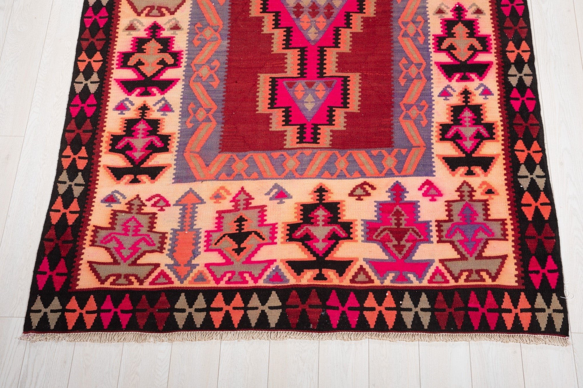 One end of the rug showing floral motifs and its beige patterned border.
