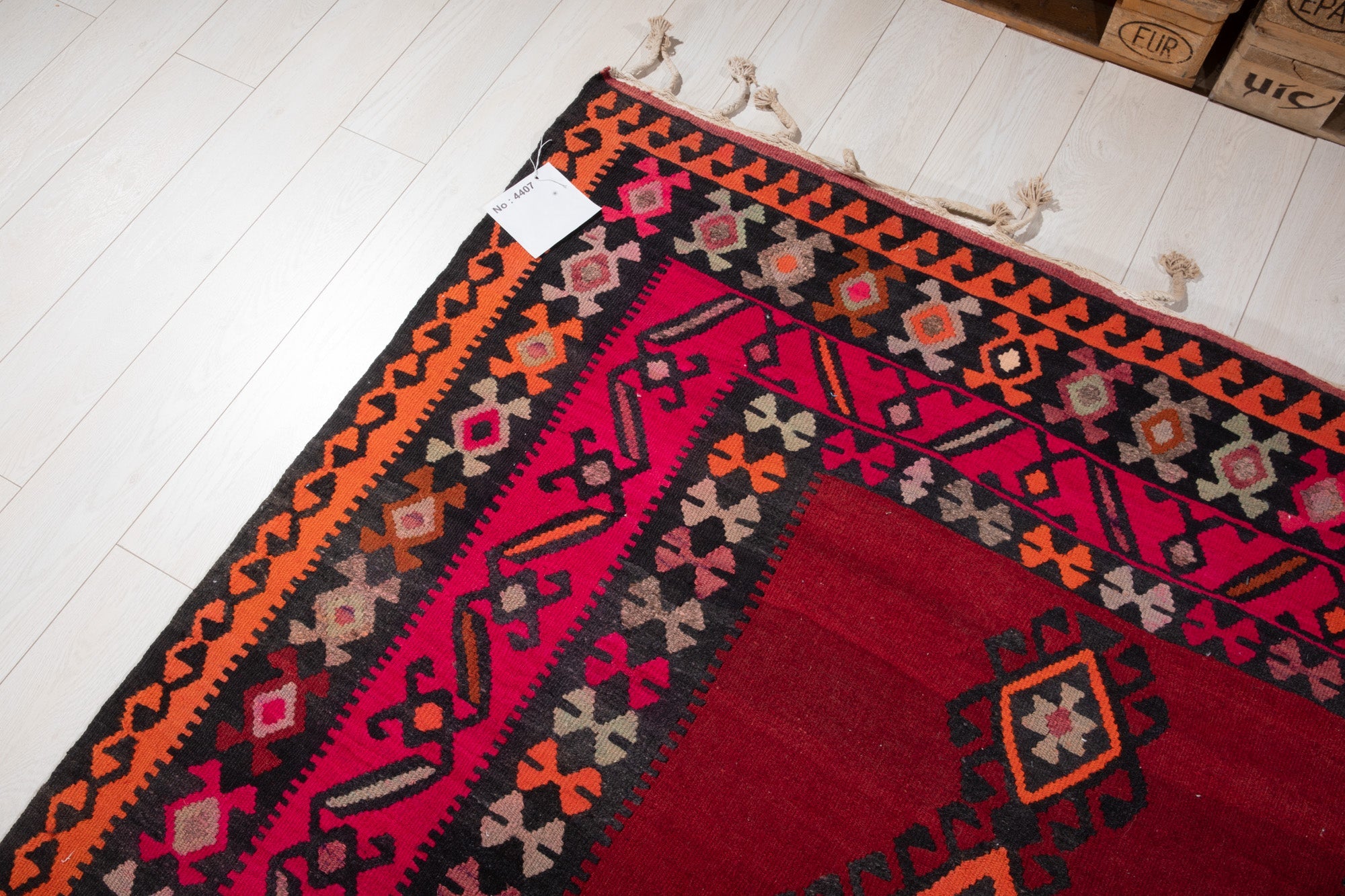 Corner of the vintage Persian Shiraz kilim runner with an attached inventory identification tag.