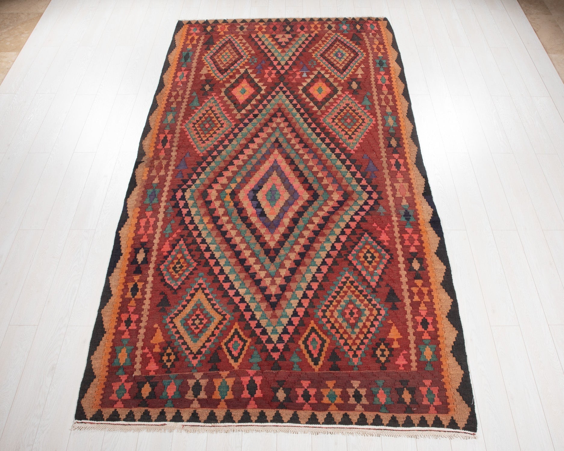 Full view of the vintage Shiraz Persian kilim rug with a bold colorful diamond medallion.