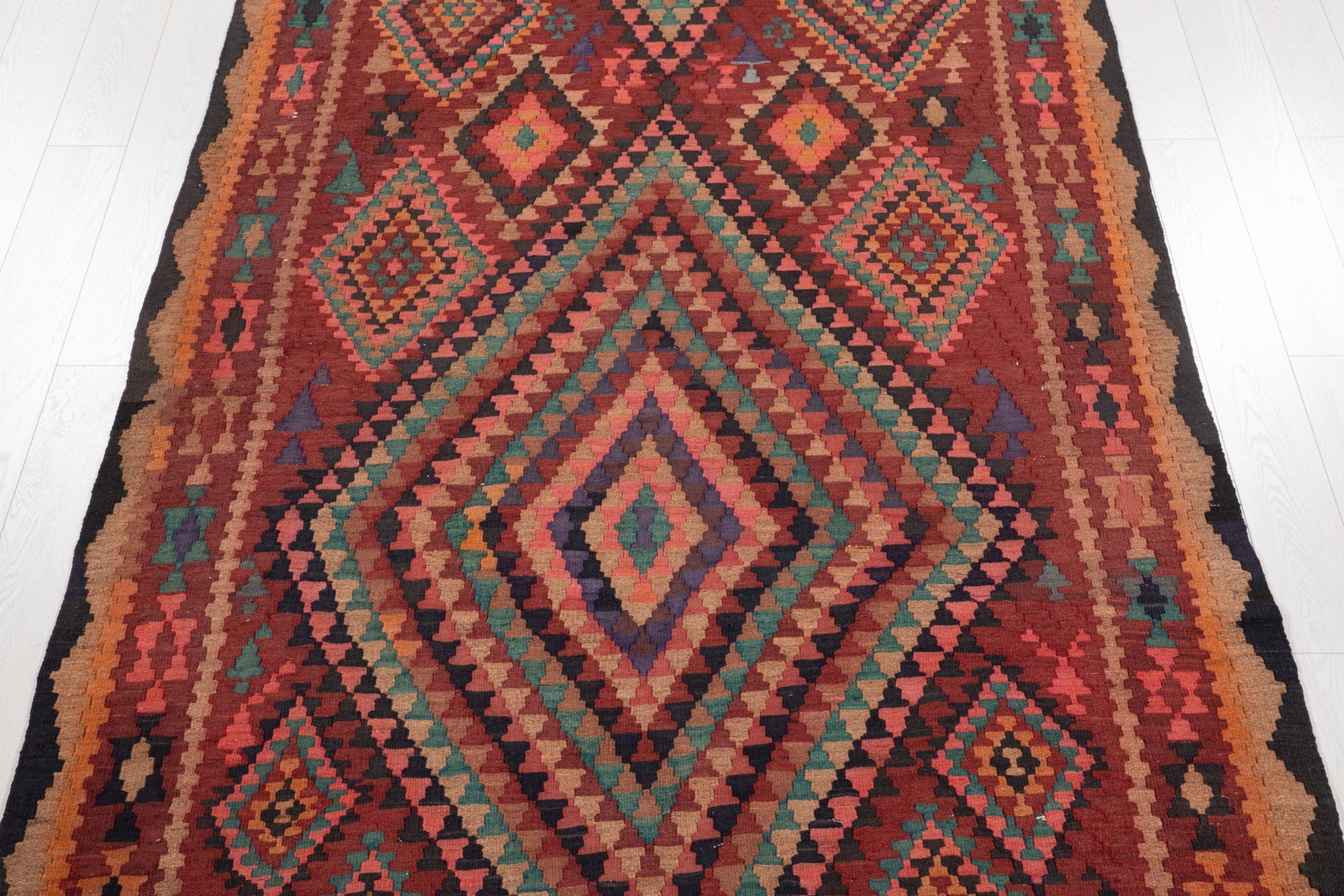 Top-down view of the kilim's concentric diamond medallions in vivid multicolor.