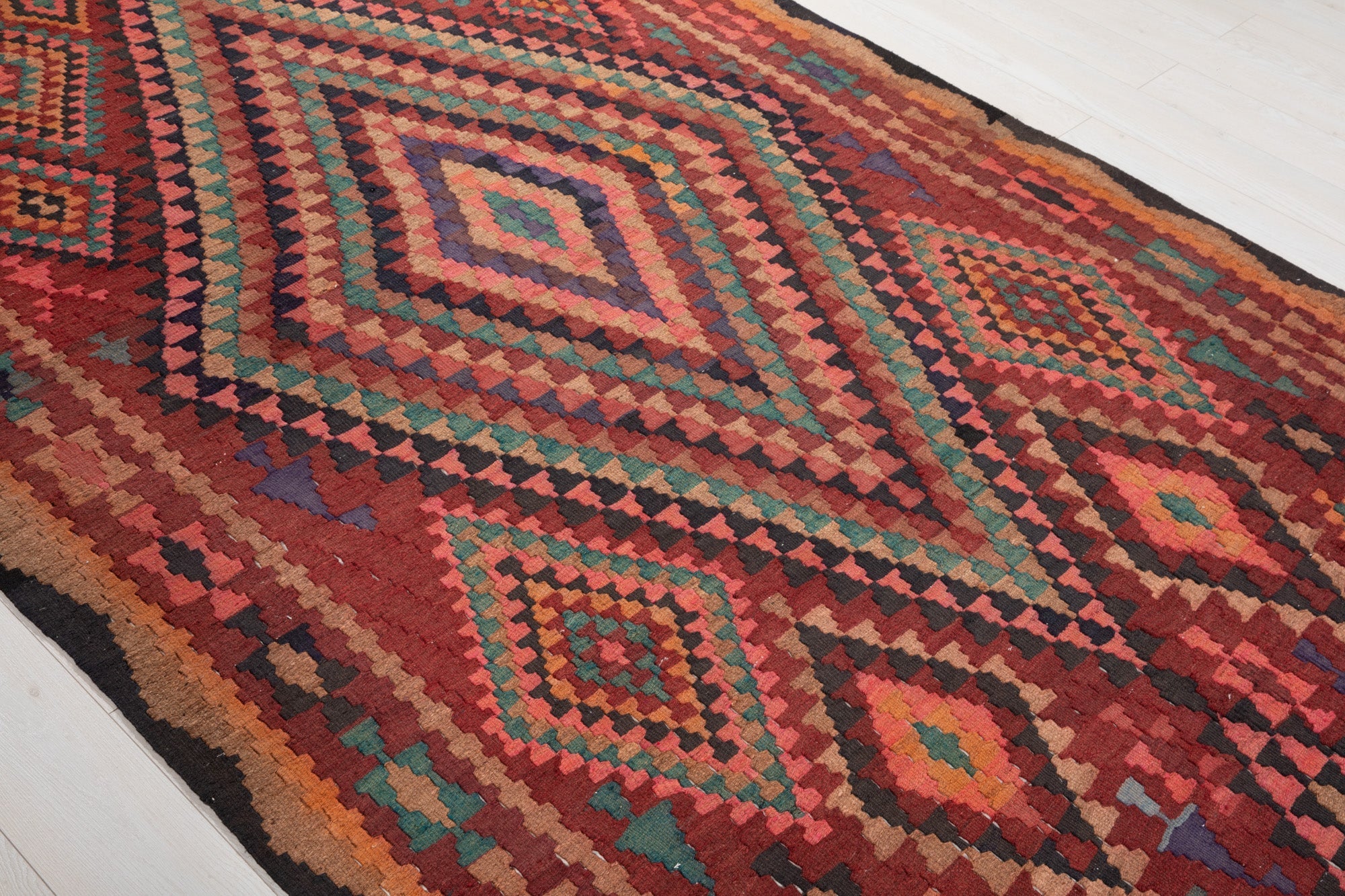 Diagonal close view of the Shiraz kilim's colorful concentric diamond medallions.