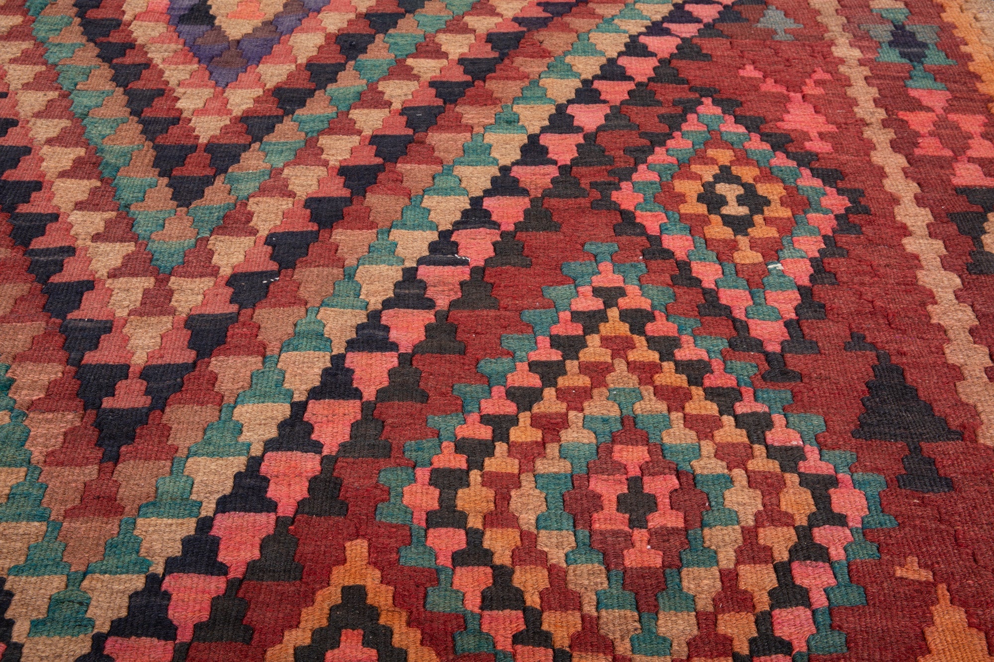 Extreme close-up of the handwoven wool kilim's colorful diamond weave texture.