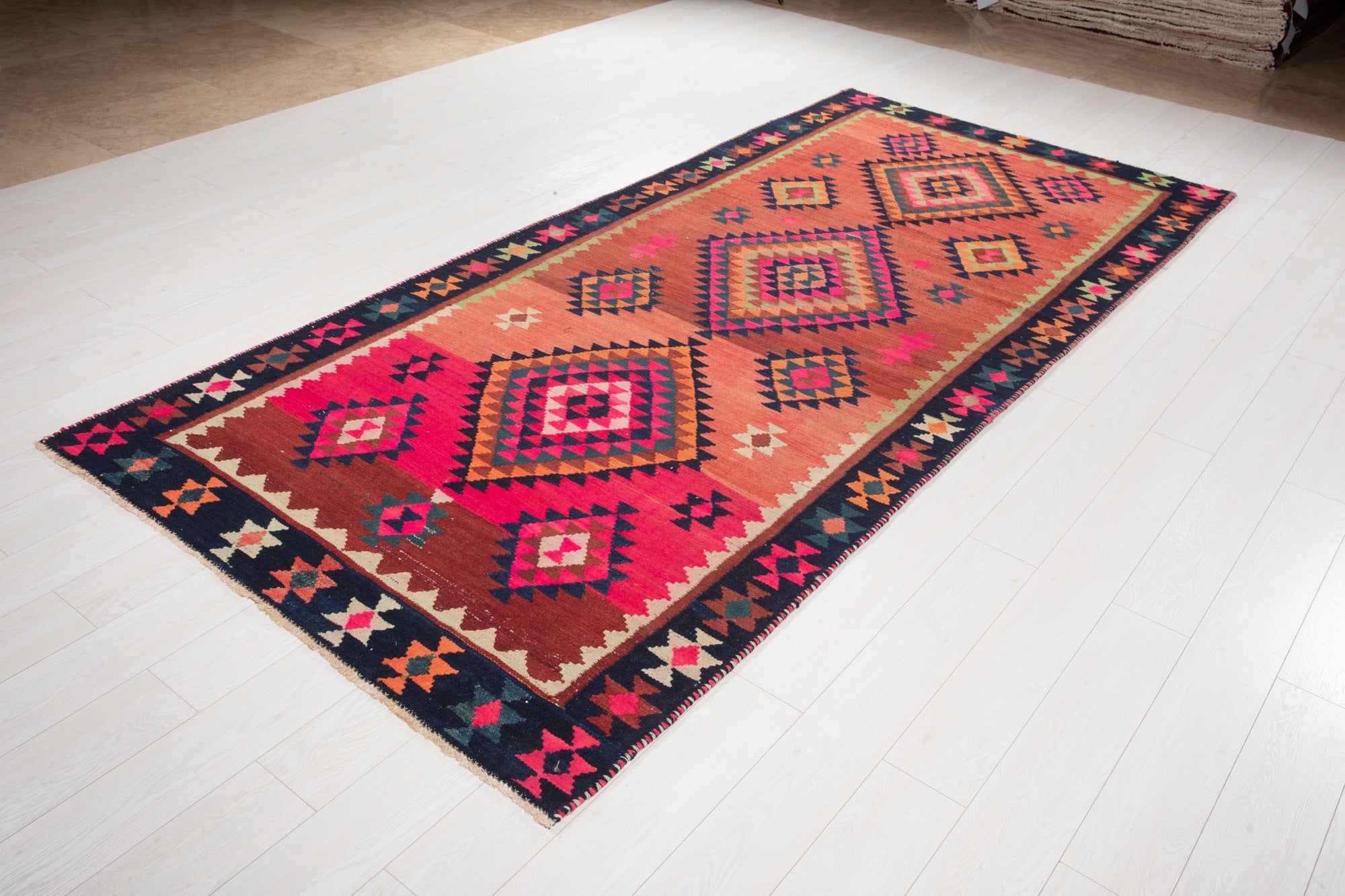 Angled view of the Shiraz Persian kilim's diamond medallions on the showroom floor.