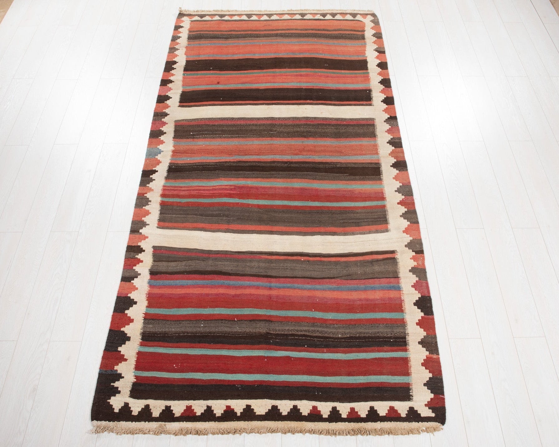 Full view of the vintage Shiraz Persian kilim rug in mid-century striped brown and red tones.