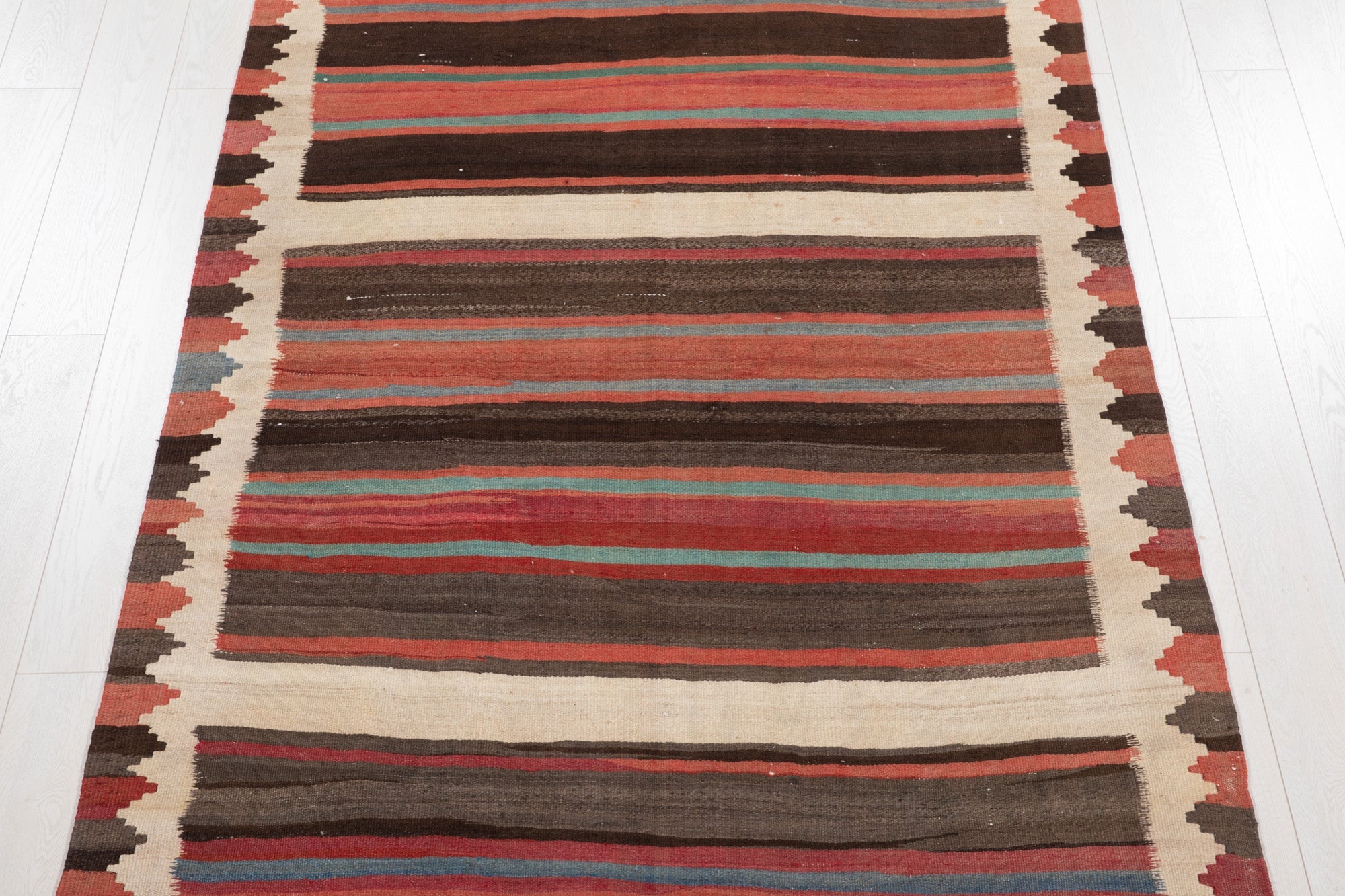 Top-down view of the kilim's horizontal stripes in brown, red and beige.