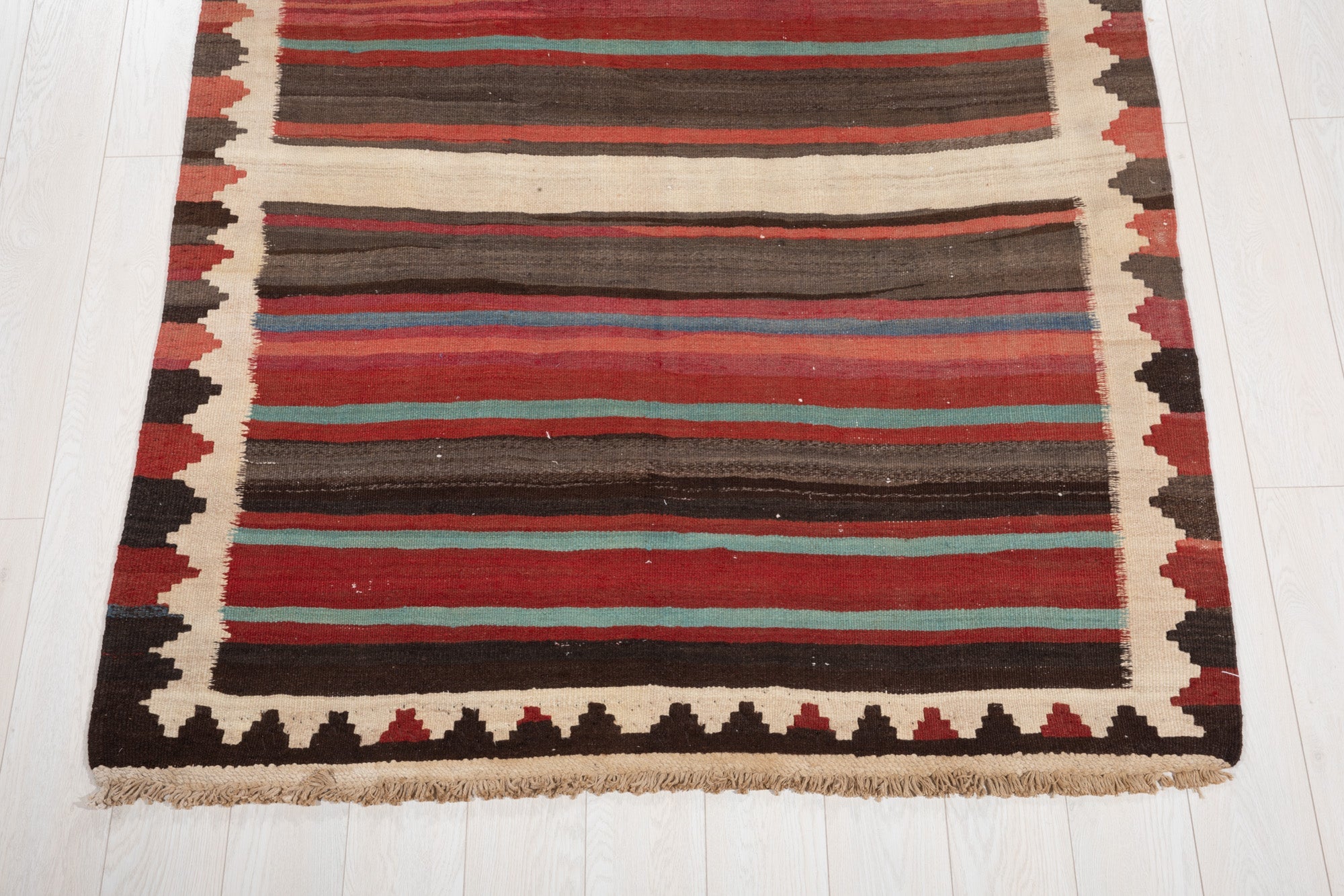 One end of the rug showing its fringe and zigzag border pattern.