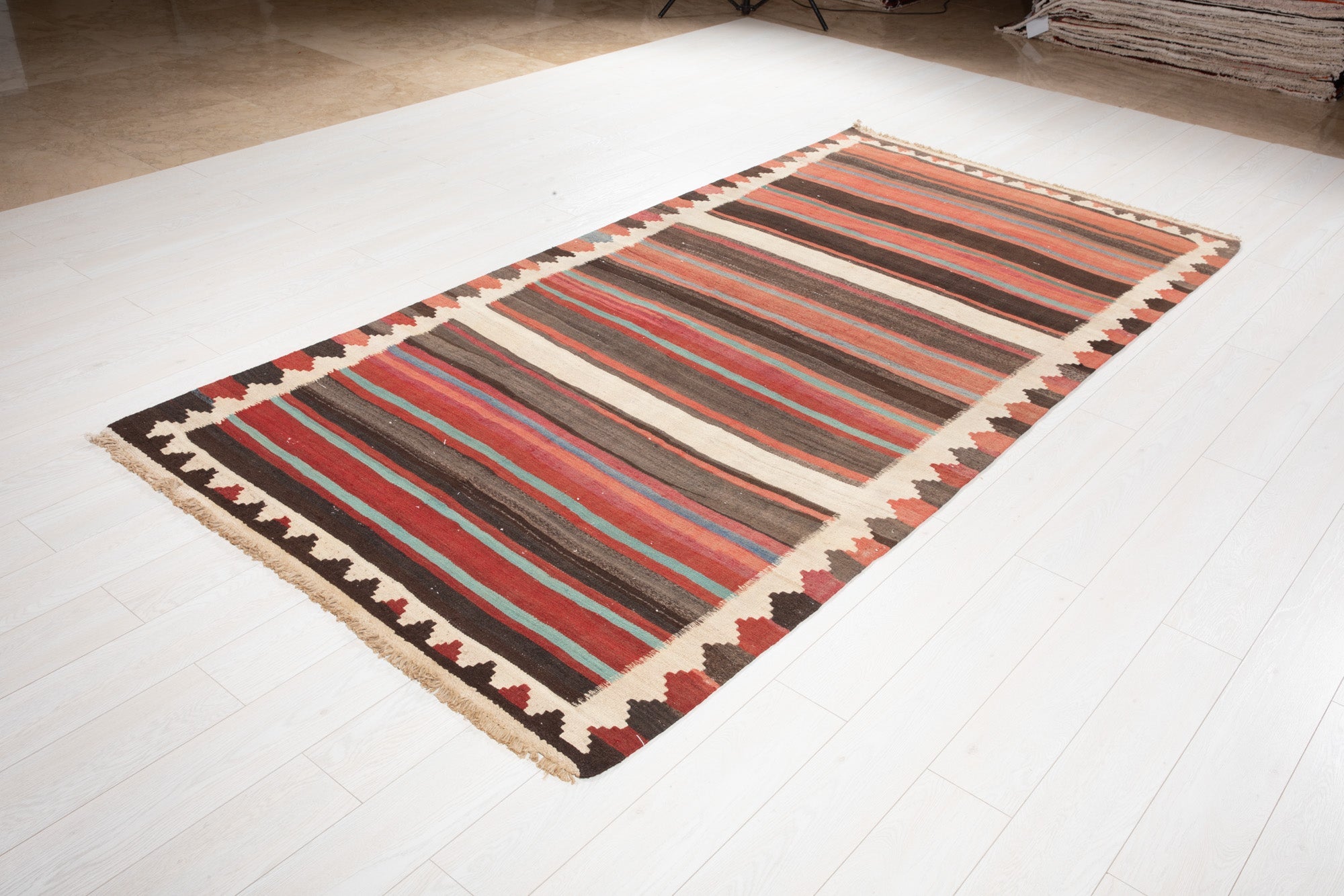 Angled view of the Shiraz kilim's striped pattern on the showroom floor.