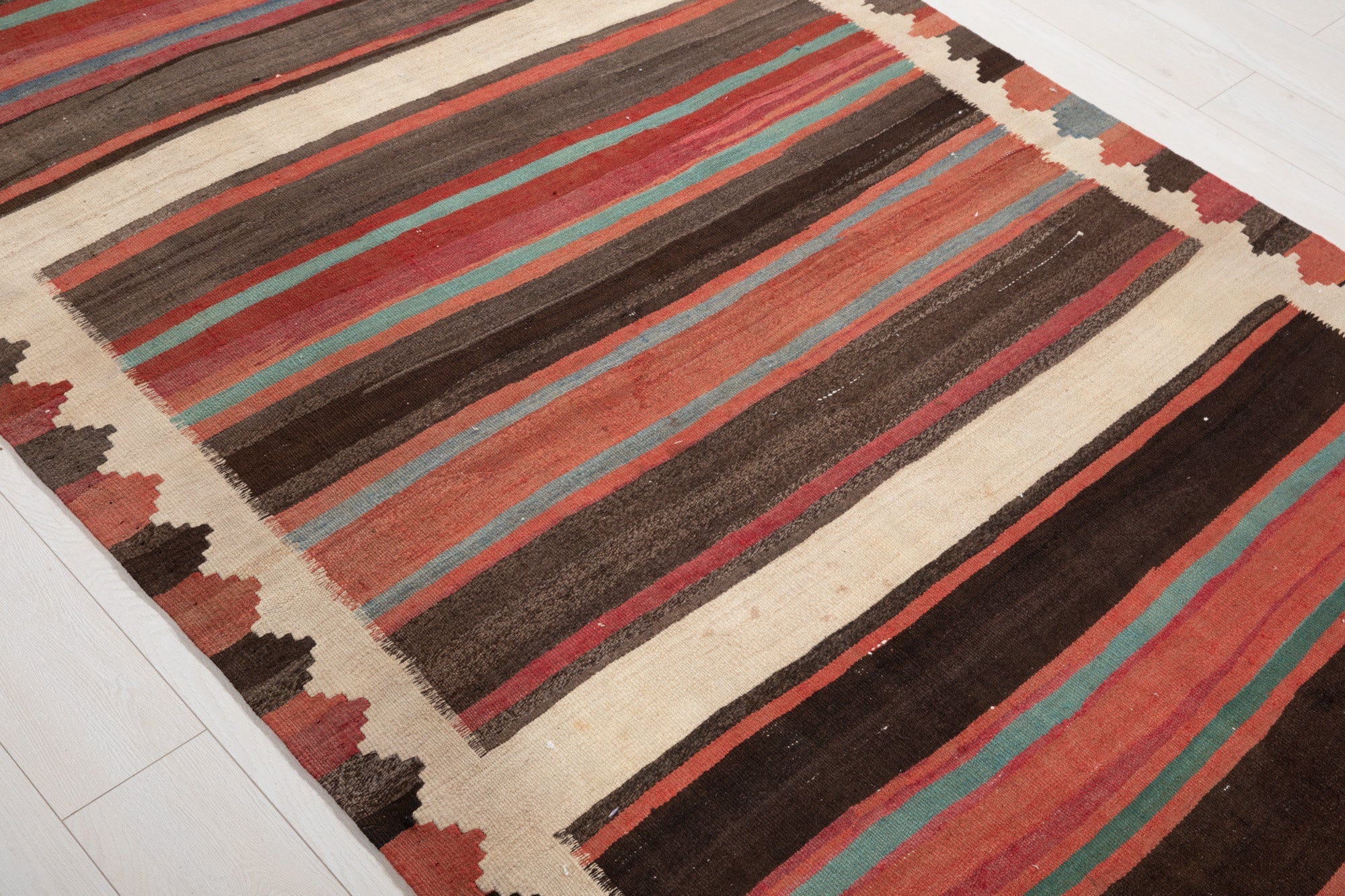 Diagonal close view of the kilim's earthy striped bands.