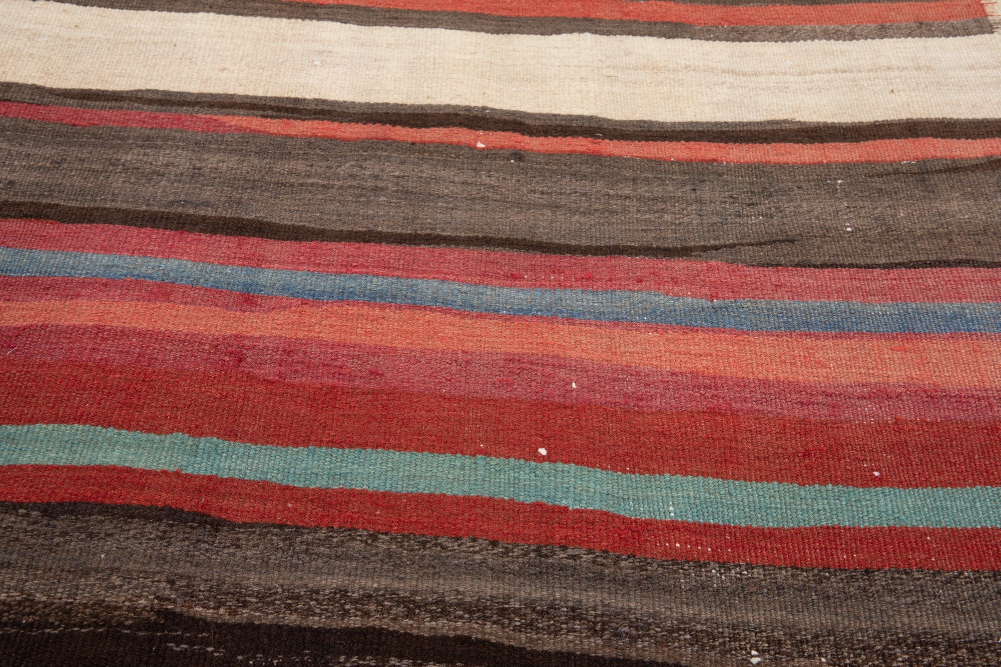 Close-up of the handwoven wool kilim's striped texture in red and teal.