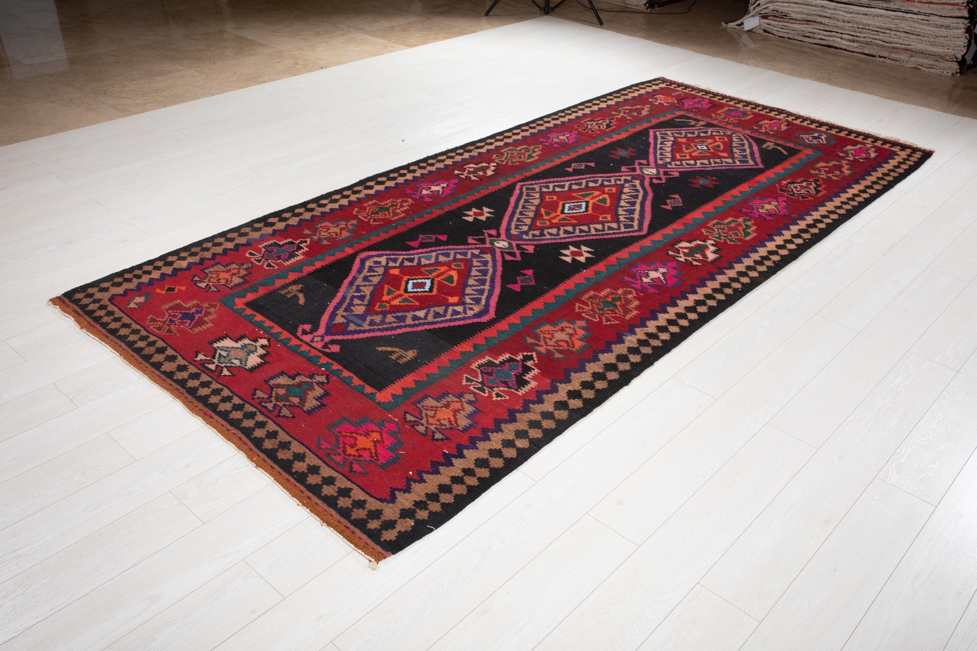 Angled view of the Shiraz kilim's diamond medallions on the showroom floor.