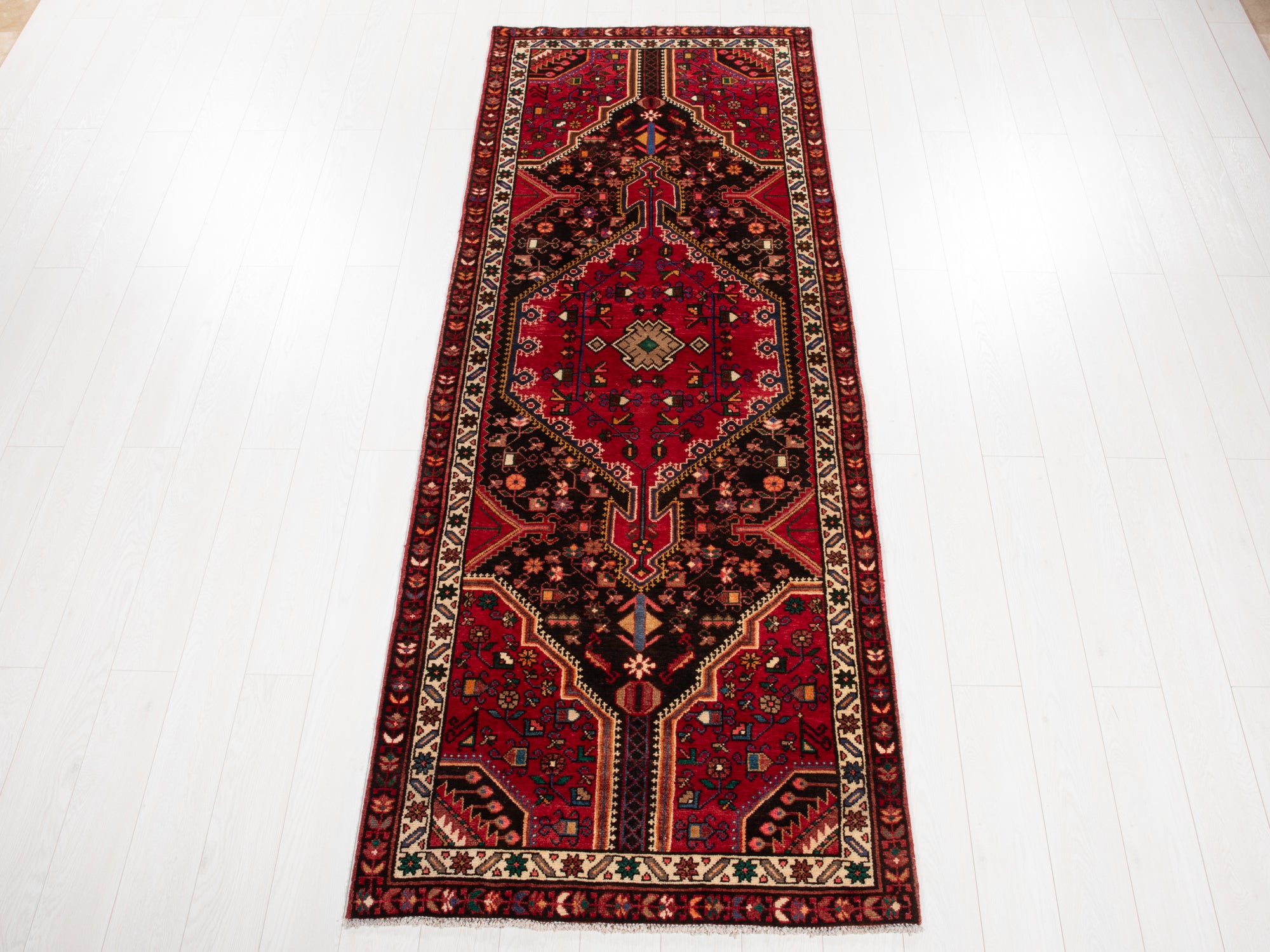 Hand-Knotted Vintage Wool Runner Rug – 9' 3" x 3' 5" with intricate red, black, and ivory geometric patterns on a white wood floor.