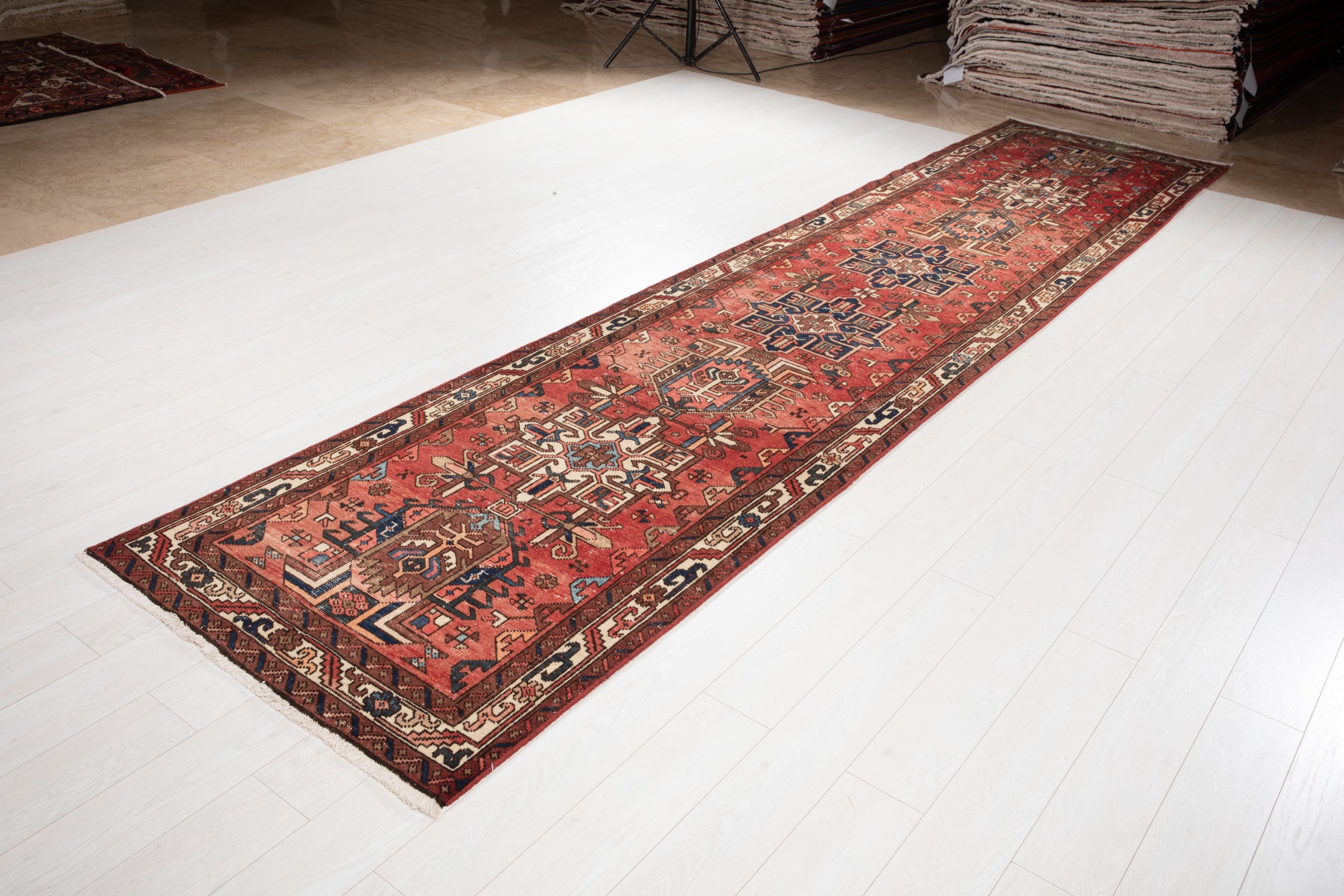 Angled view of Hand-Knotted Antique Wool Runner Rug – 14' 9" x 3' 4" laid on white floor, showing full length and traditional border design.
