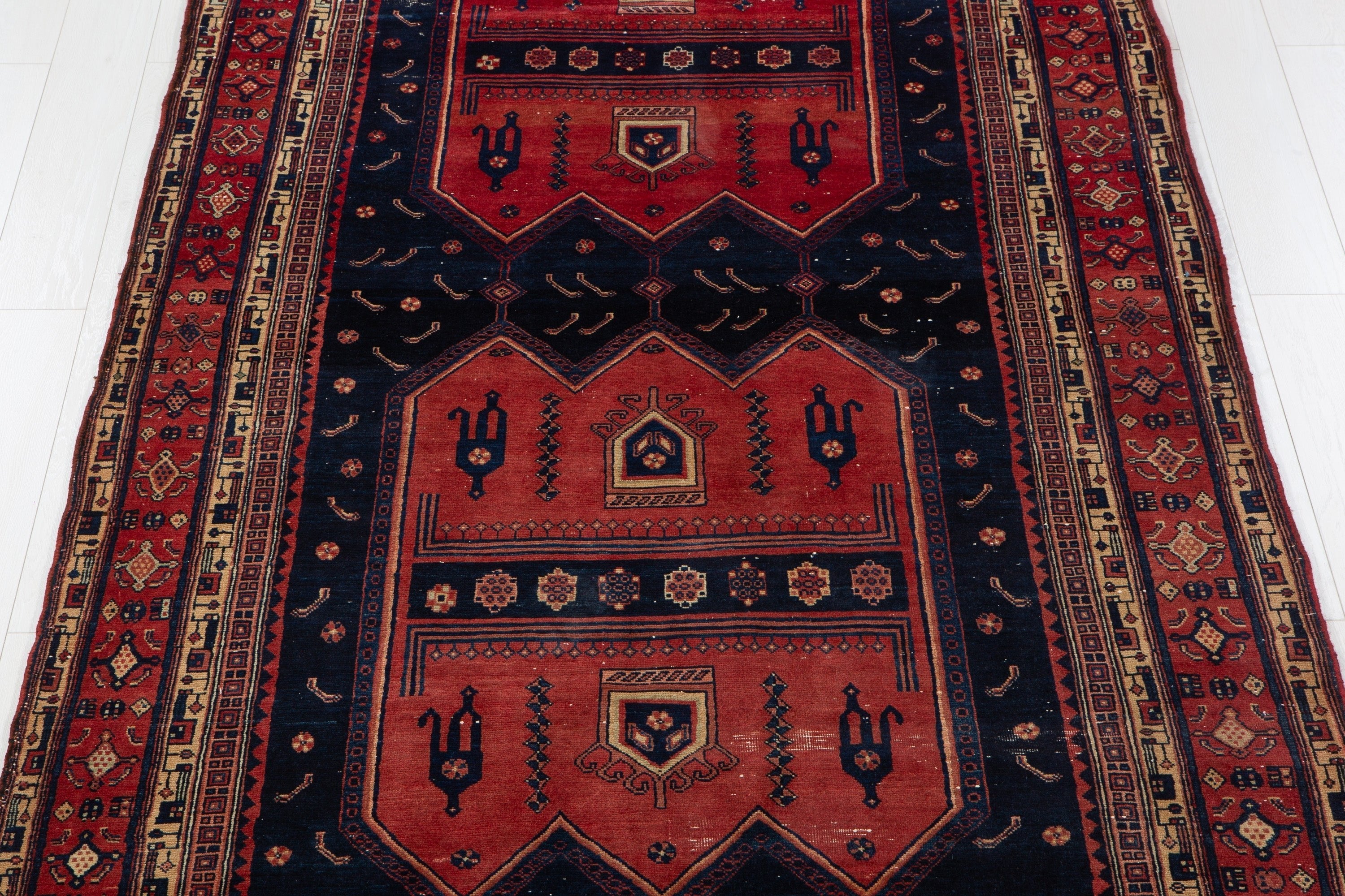 Close-up of the rug's red and navy medallion pattern, highlighting the tribal motifs in detail.