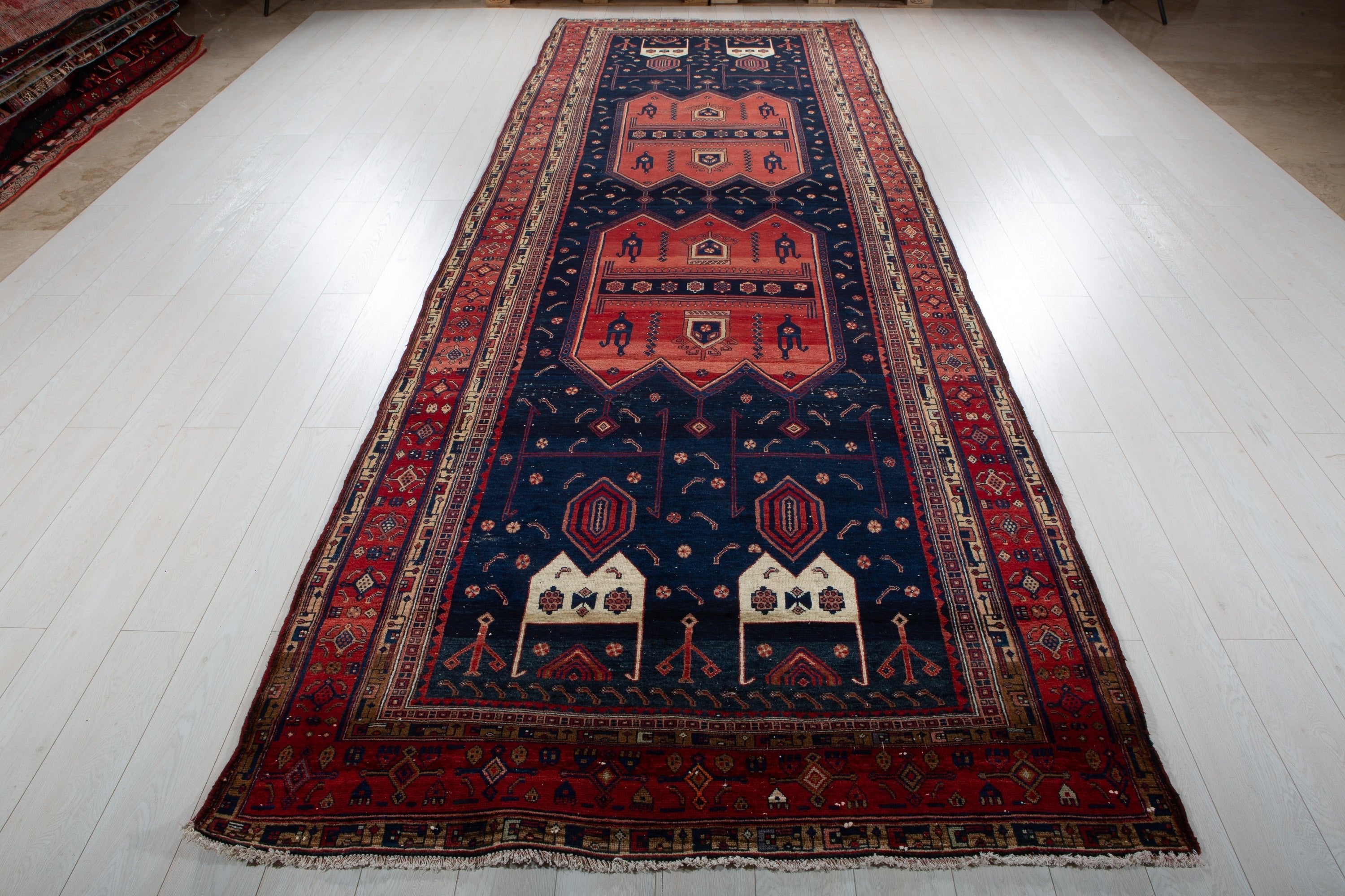 Full-length perspective view of the rug from one end, showing the entire red and navy tribal design.