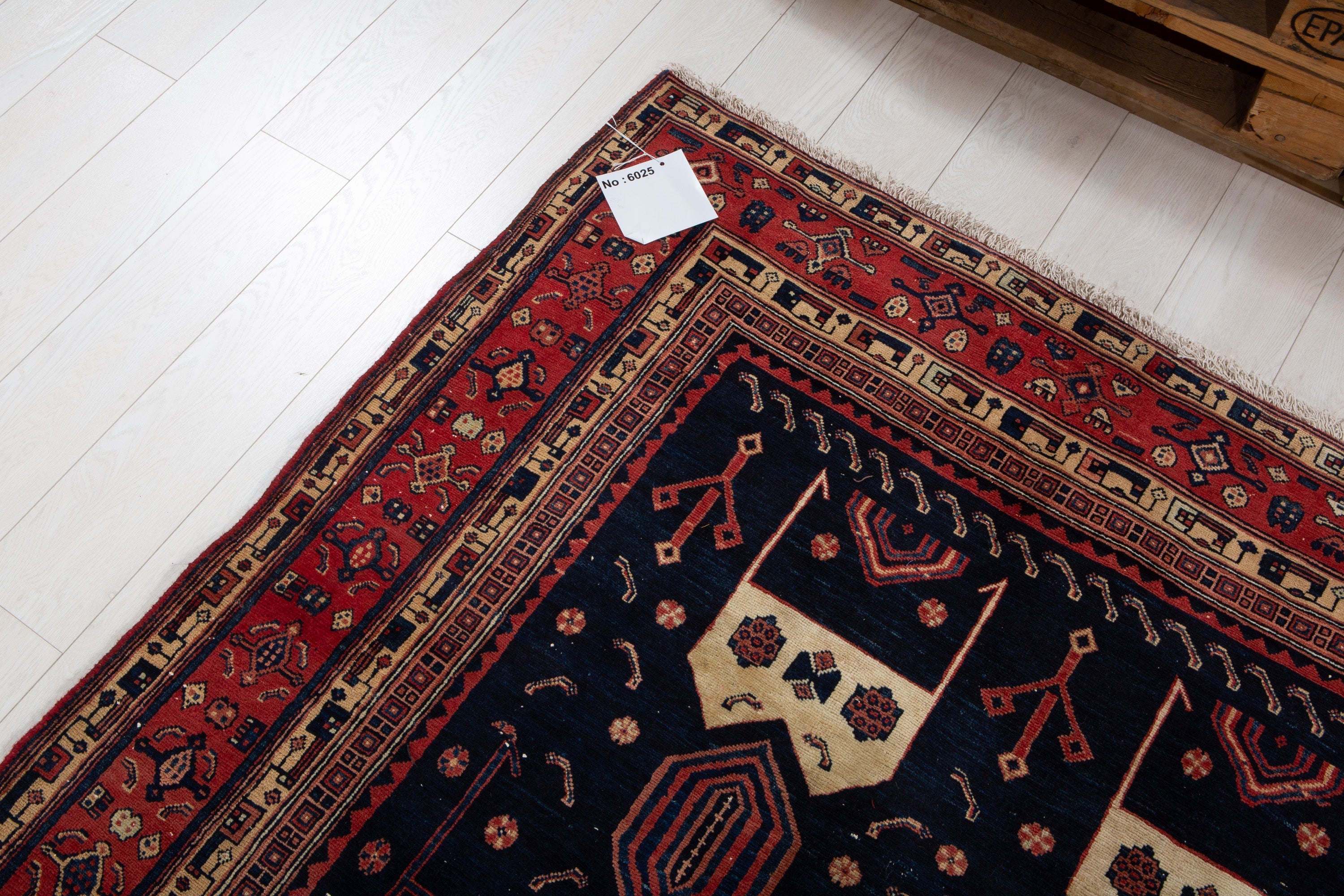 Corner detail of the rug's border pattern with an attached inventory identification tag.