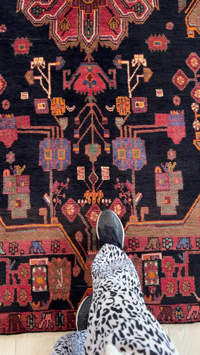 Close-up of Hand-Knotted Vintage Wool Area Rug – 9' 2" x 4' 11" highlighting the colorful floral and geometric designs with a foot for scale.
