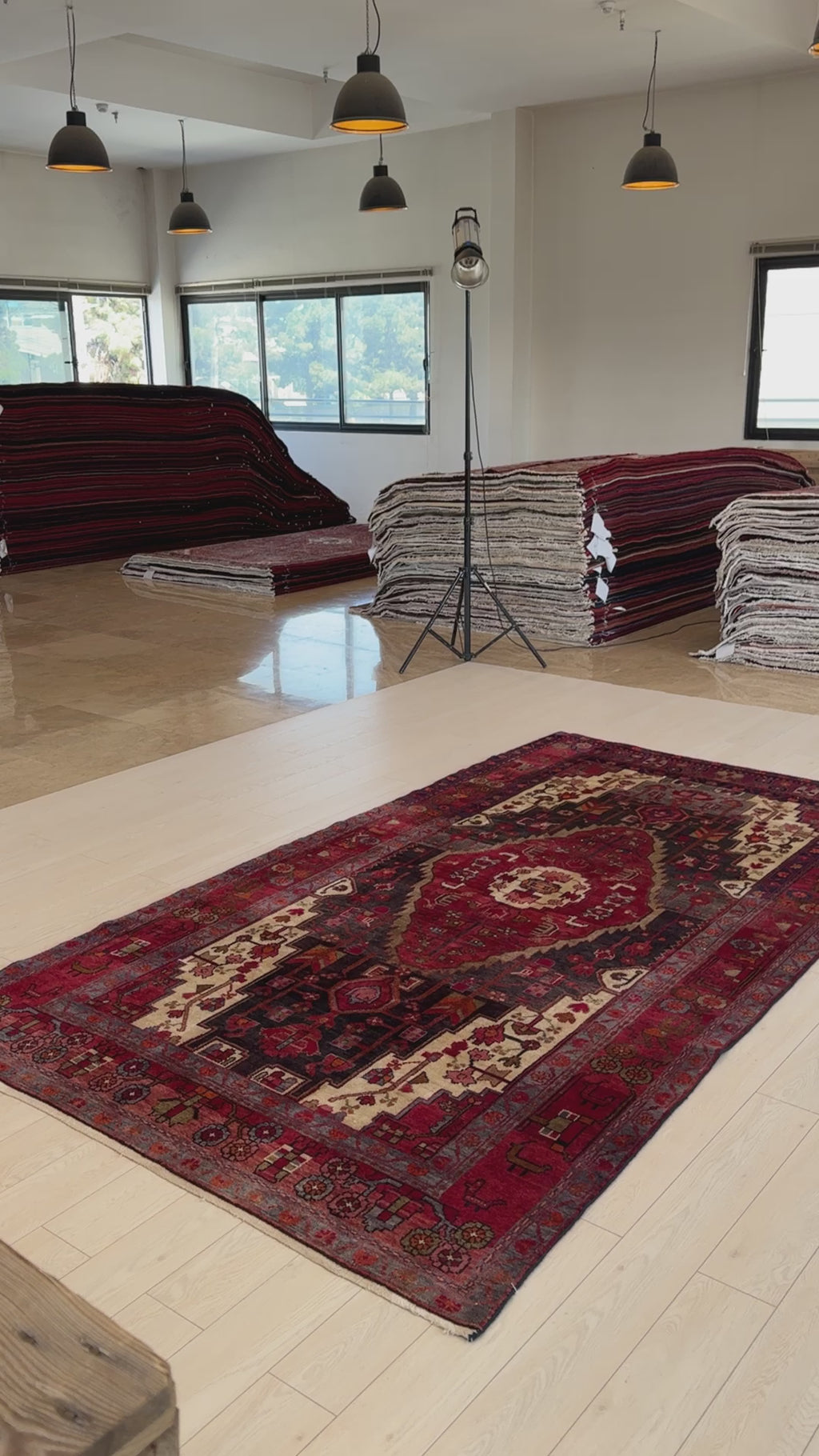Hand-knotted vintage wool rug 10'1 x 5'6 laid flat in a bright showroom, highlighting its bold geometric design and deep red hues.