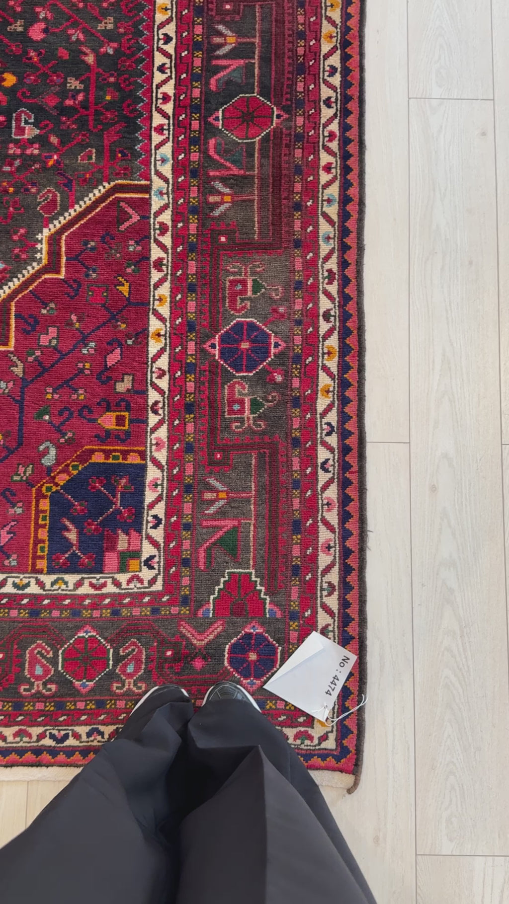 Close-up corner of Hand-Knotted Vintage Wool Area Rug – 10' 6" x 5' 5" showing detailed border design and vibrant red and black color scheme.