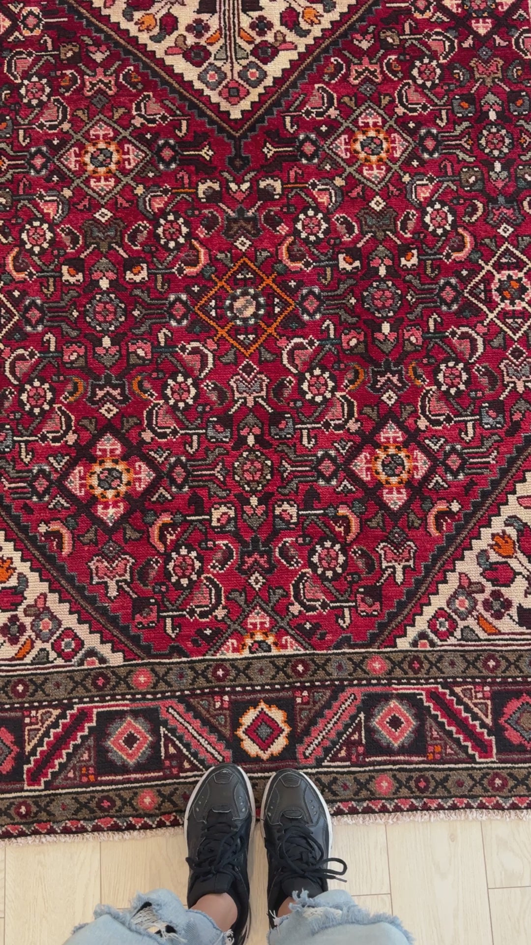 Close-up of Hand-Knotted Vintage Wool Area Rug – 10' 8" x 5' 2" showing detailed floral patterns and vibrant red hues underfoot.