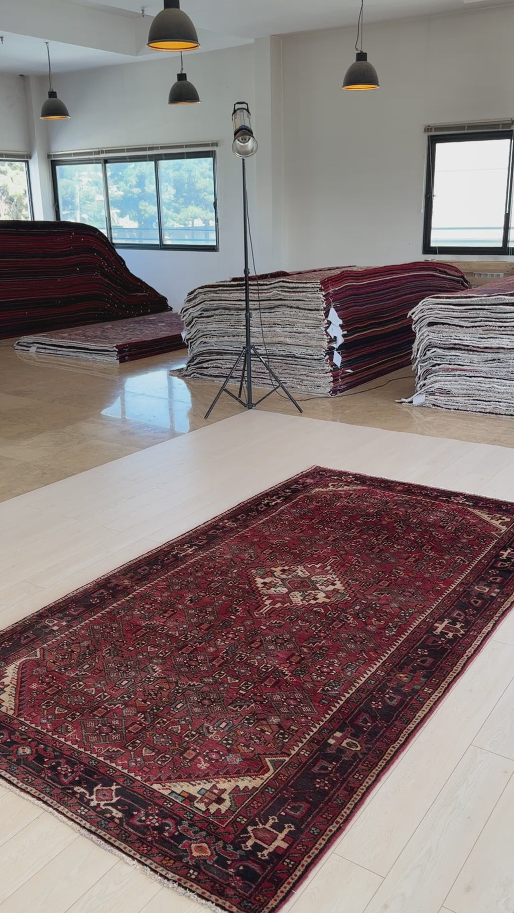 Hand-Knotted Vintage Wool Area Rug – 9' 7" x 5' 3" laid out in a showroom with natural lighting, surrounded by stacked rugs in the background.