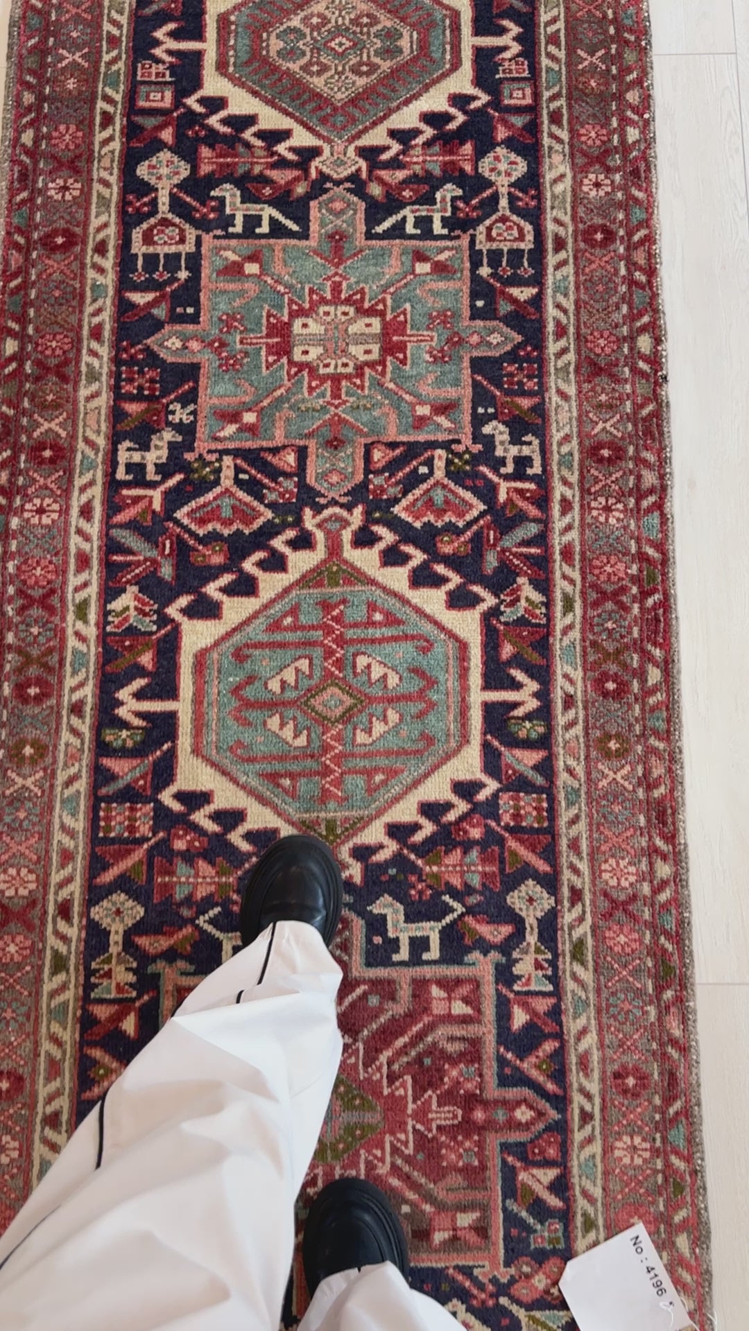 Detailed view of vintage wool runner rug 10' 9" x 2' 10" with tribal medallions and person standing on it for size reference.